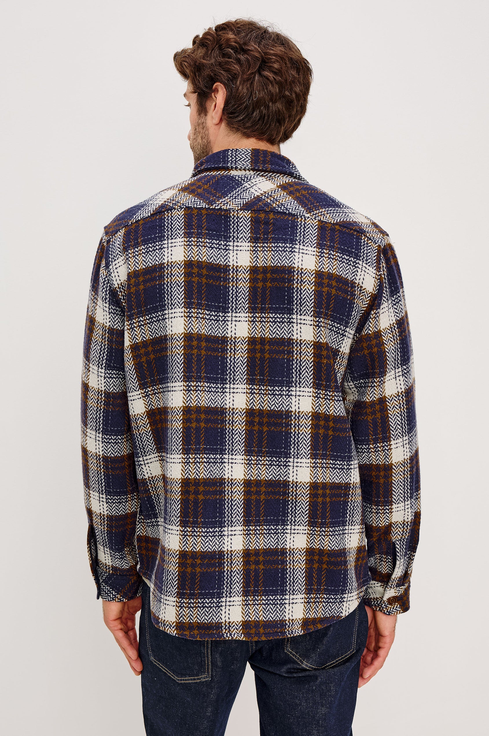 The Berkshire is a plaid shirt jacket with two chest pockets button front and collar in Navy Umber Cream colorway. Back view featured on model.