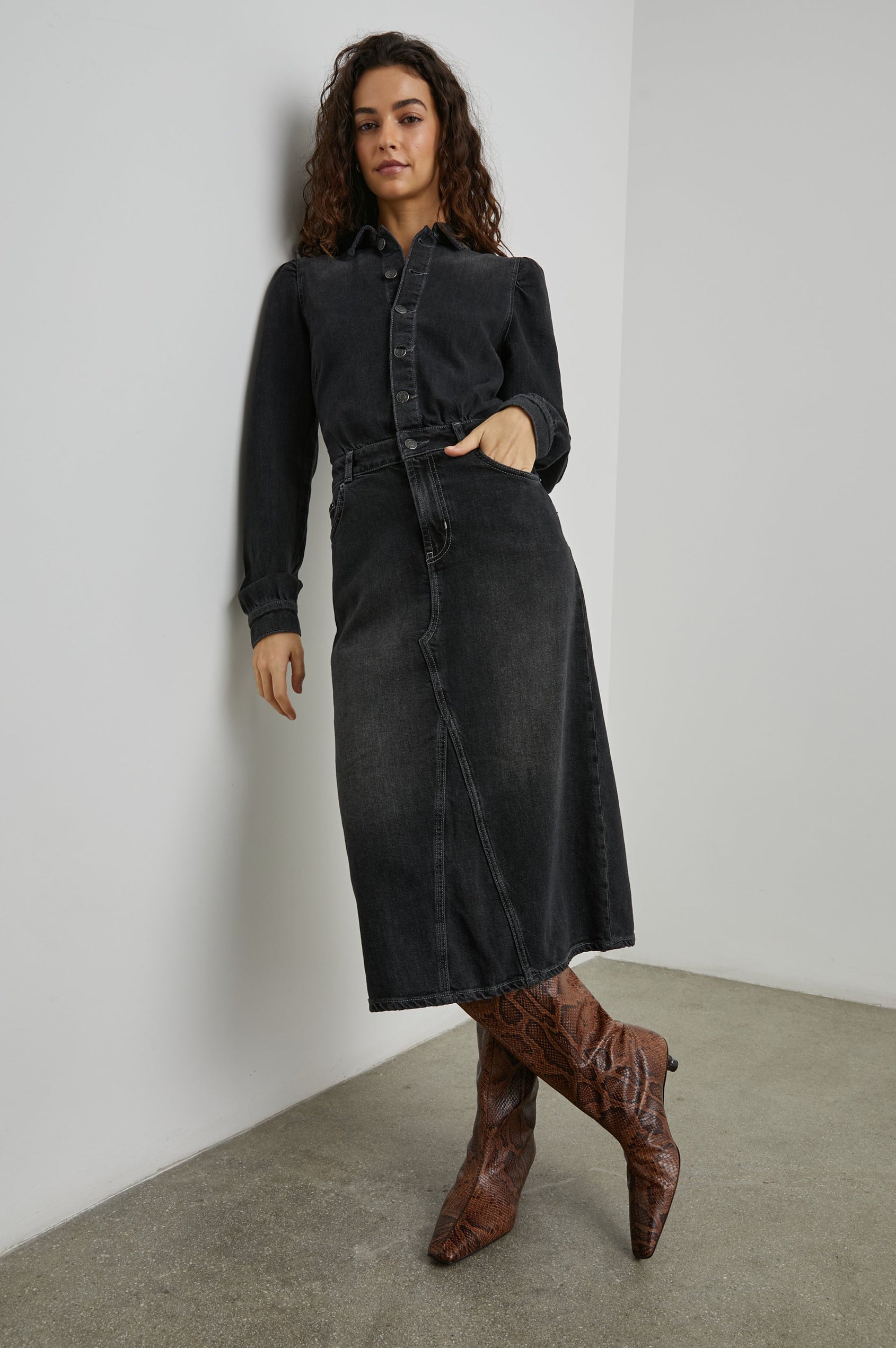 Beverly Long Sleeve Denim Knee Dress with a Back Vent, Belt Loops, a Button and Zipper Closure for the Skirt and Button Closure on the Bodice, a Collar, two Front Pockets plus a Coin Pocket and Two Back Patch Pockets in Eclipse Colorway, a Black - Front Full Body View Featured on Model