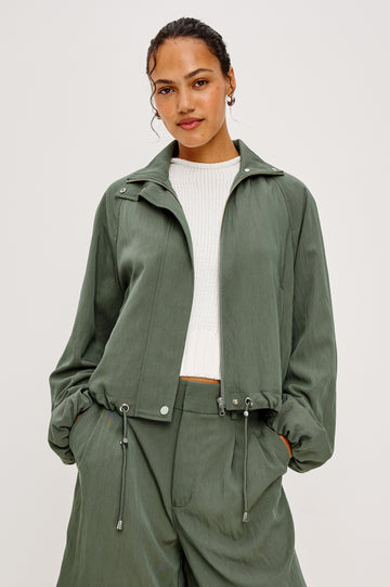 Black Jacket With Oversized Relaxed Fit High Funnel Neck Dropped Shoulders Long Sleeves Center-Front Ties Side-Seam Zipper in Ivy Colorway - Upper Body Front Close Up View Featured on Model