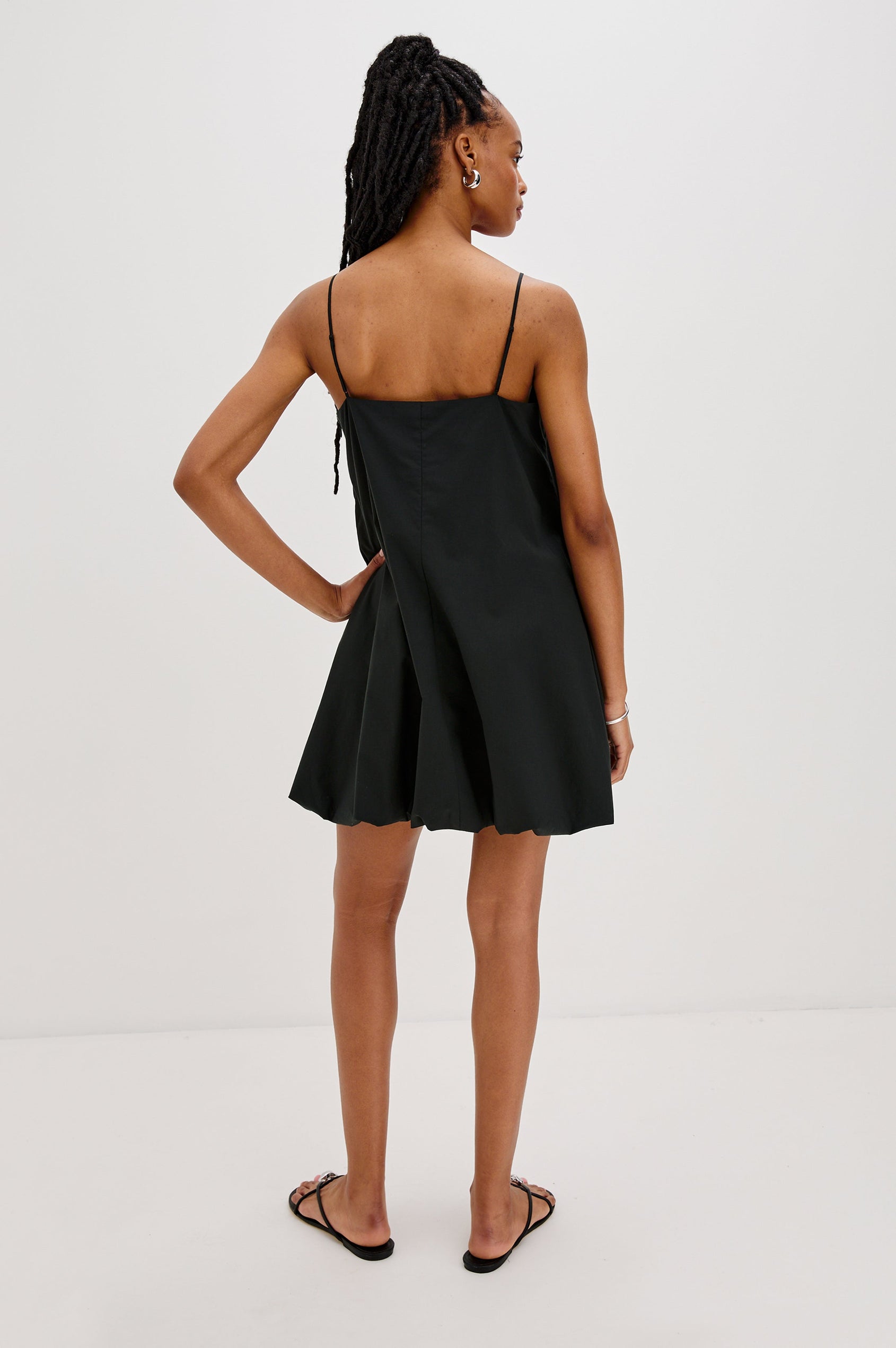 Blanca Bubble Hem Mini Dress with Spaghetti Straps and Side Pockets. Full Body Back View Shown on Model.