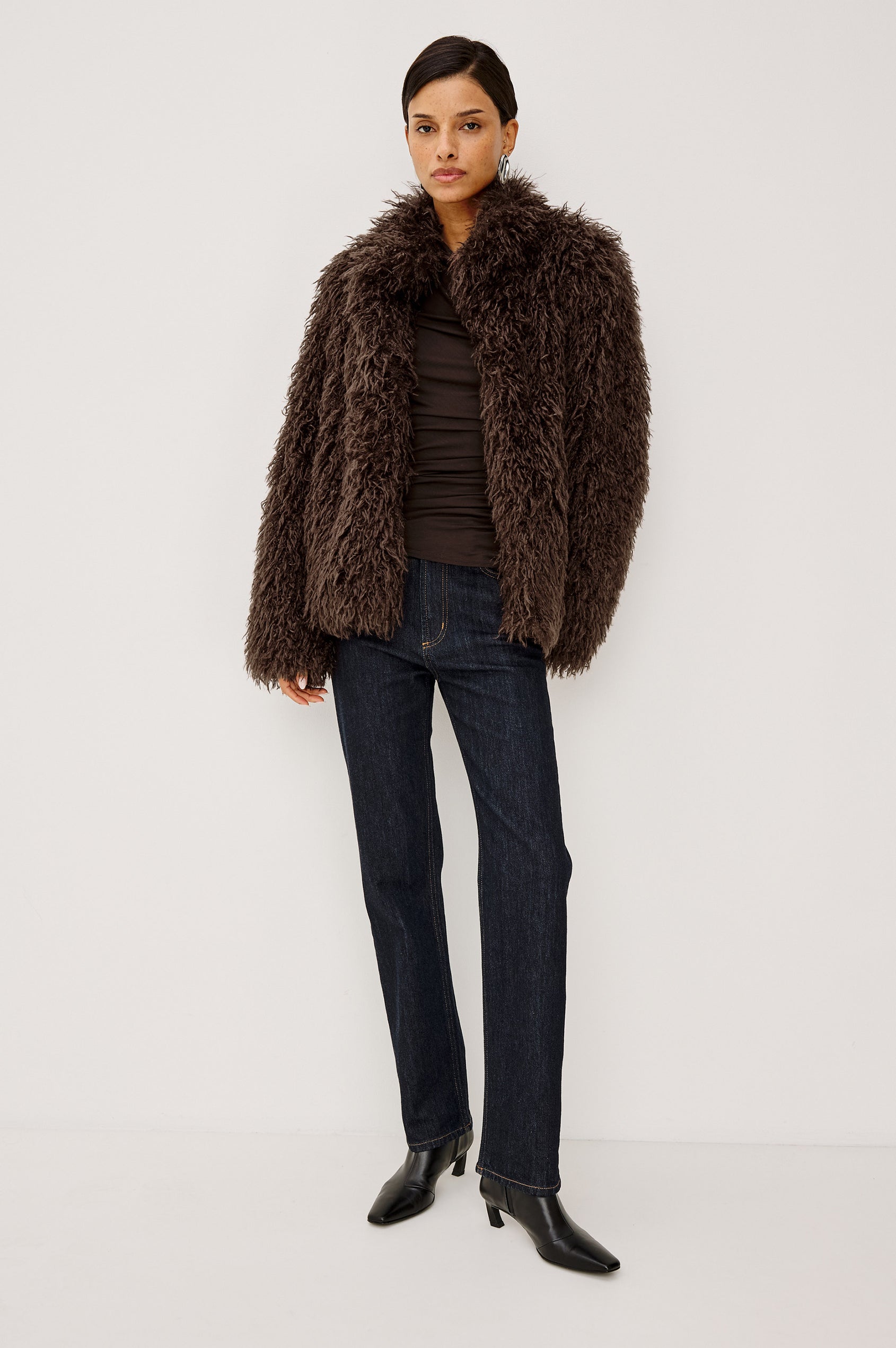 Blisse Jacket in Faux Mongolian Fur With Boxy Slightly Cropped Cropped Silhouette, Collar, Satin-Like Lining, Side Pocketts, and Front Hook-And-Eye Closure in Espresso Colorway - Full Body Front View Featured on Model