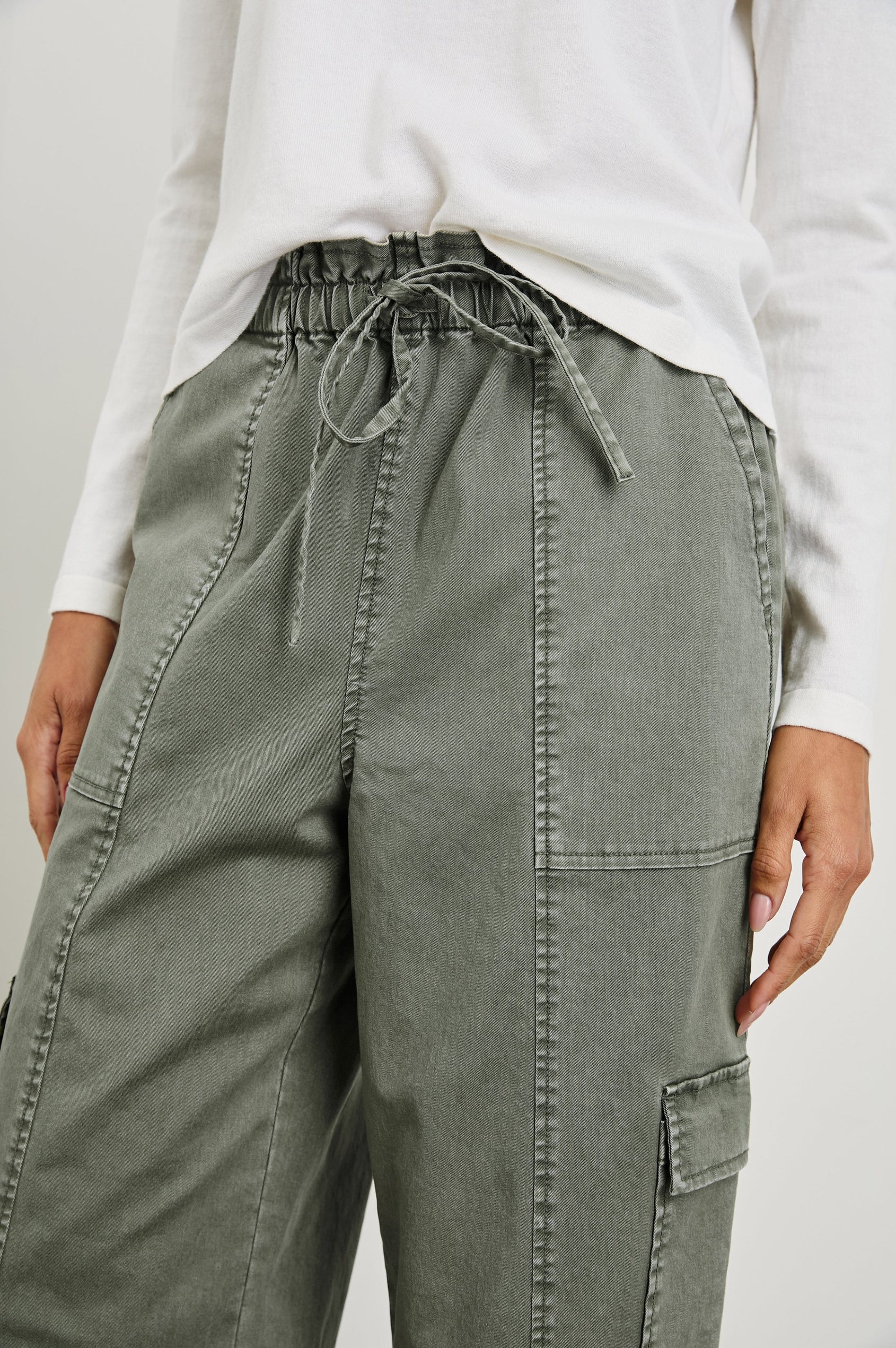 Bodie Pants with a Drawstring Waist, Front and Back Center Vertical Leg Seams, Two Front Pockets, Two Flap Side Pockets and Two Back Welt Pockets in Dark Olive Colorway - Front View Featured on Model  