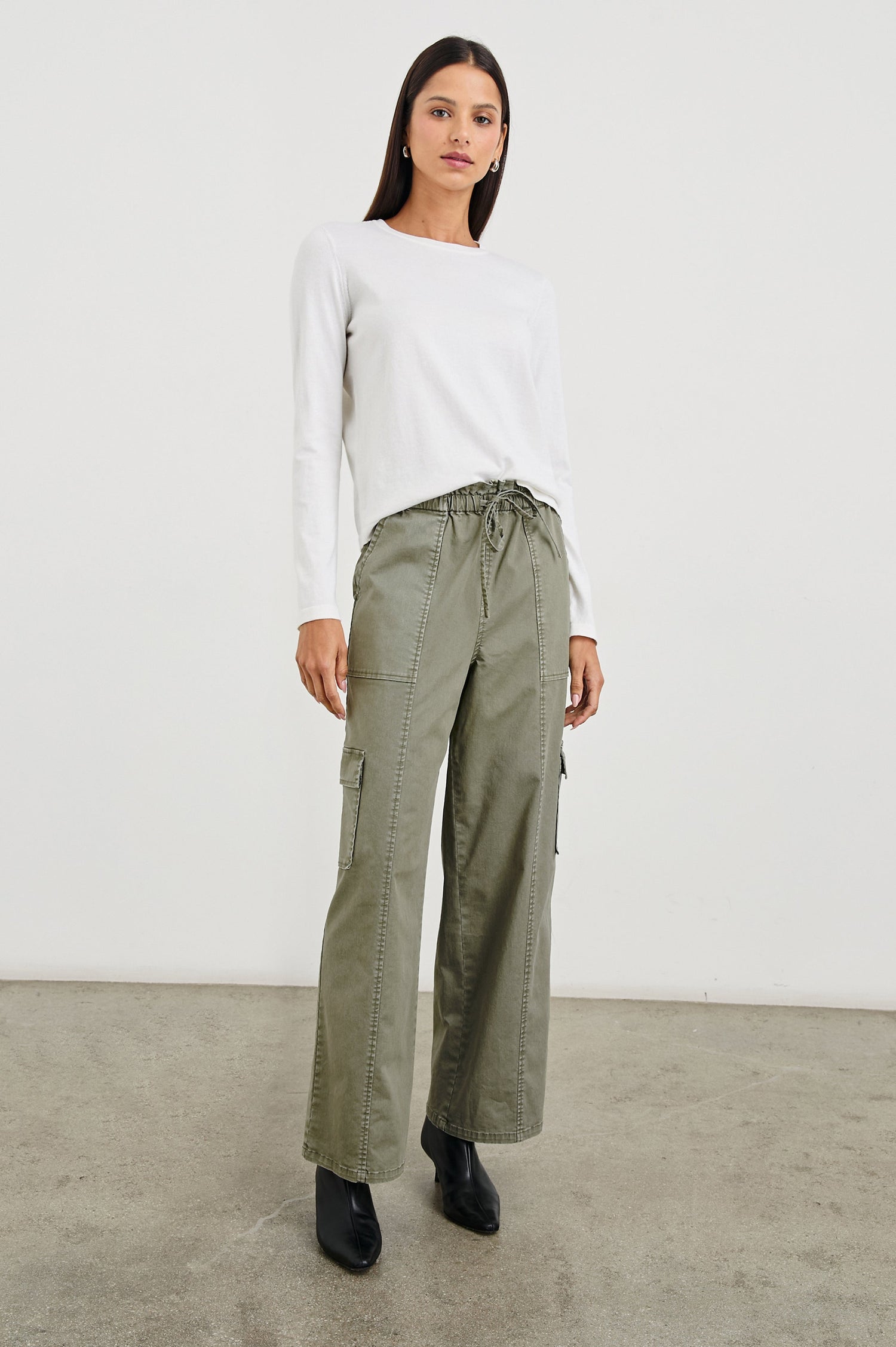 Bodie Pants with a Drawstring Waist, Front and Back Center Vertical Leg Seams, Two Front Pockets, Two Flap Side Pockets and Two Back Welt Pockets in Dark Olive Colorway - Front Full Body View Featured on Model  