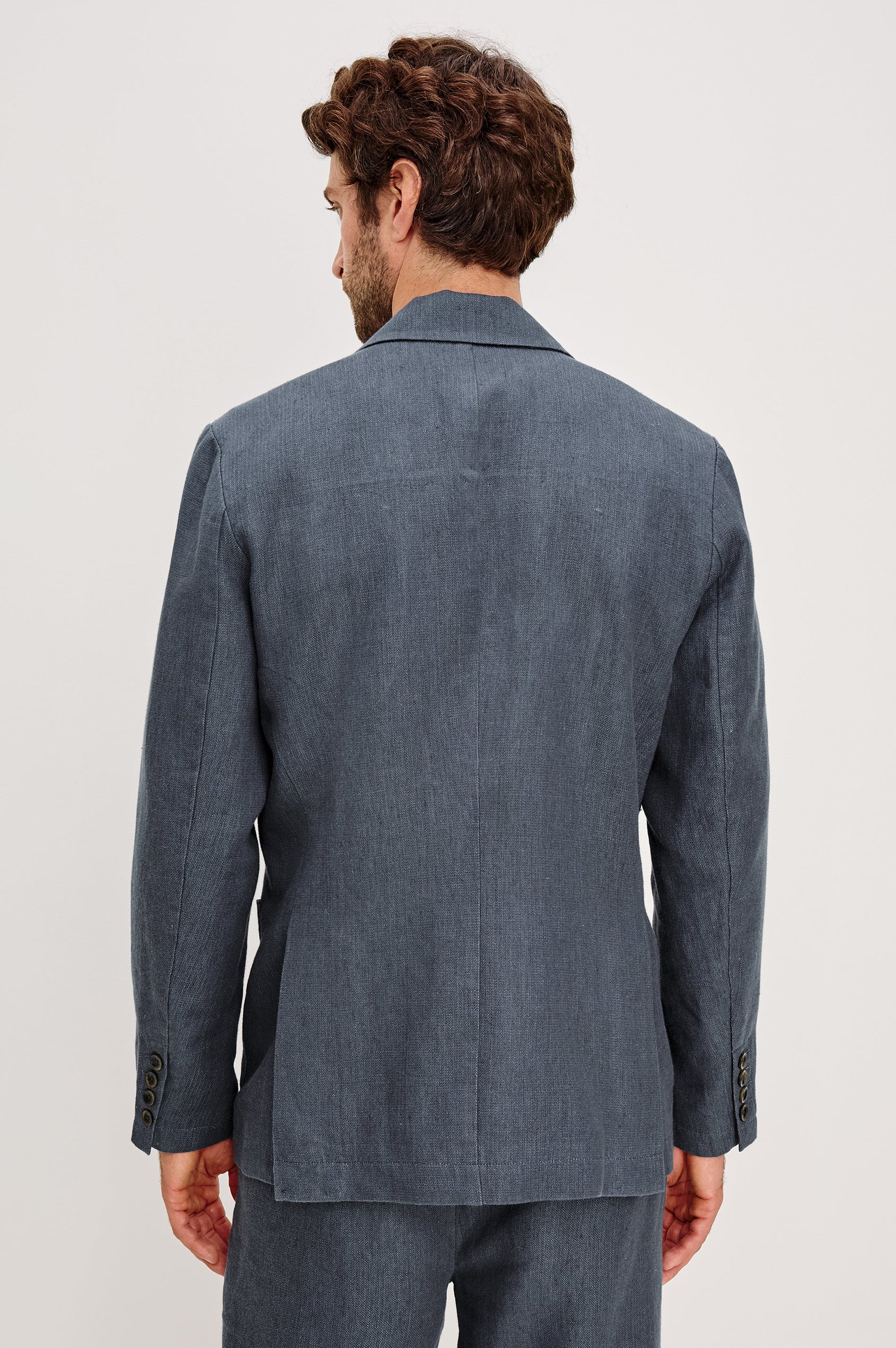 The Bond is a single breasted blazer with two buttons, one chest pocket and two patch pockets in a blue Meridian colorway. Back view featured on model.