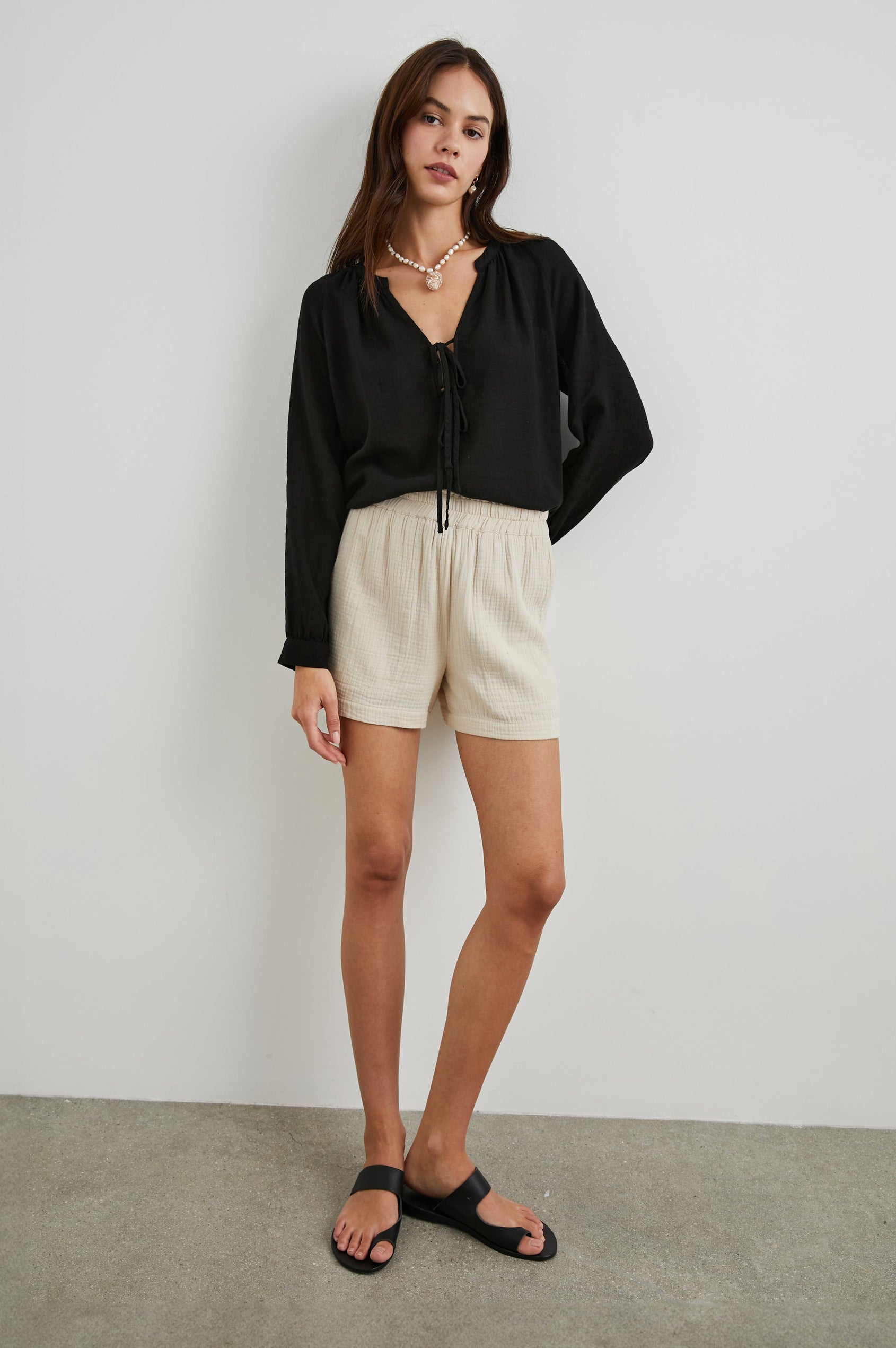 Brielle Long-Sleeve Top with a Deep V Neck with Ties and Pleats around the Neckline in Black Colorway - Front Full Body View Featured on Model