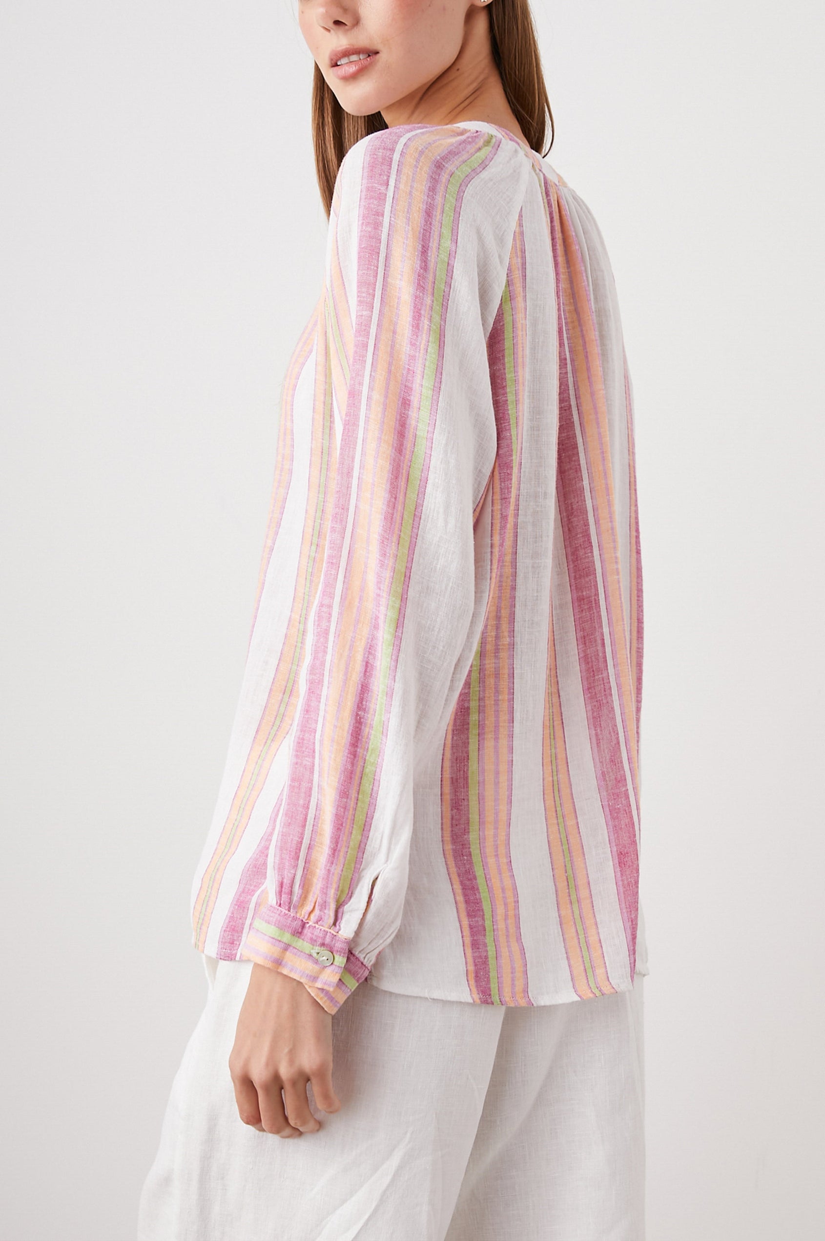 Brielle Long-Sleeve Top with a Deep V Neck with Ties and Pleats around the Neckline in Hibiscus Stripe Colorway, with vertical pinks, green and white stripes - Side View Featured on Model