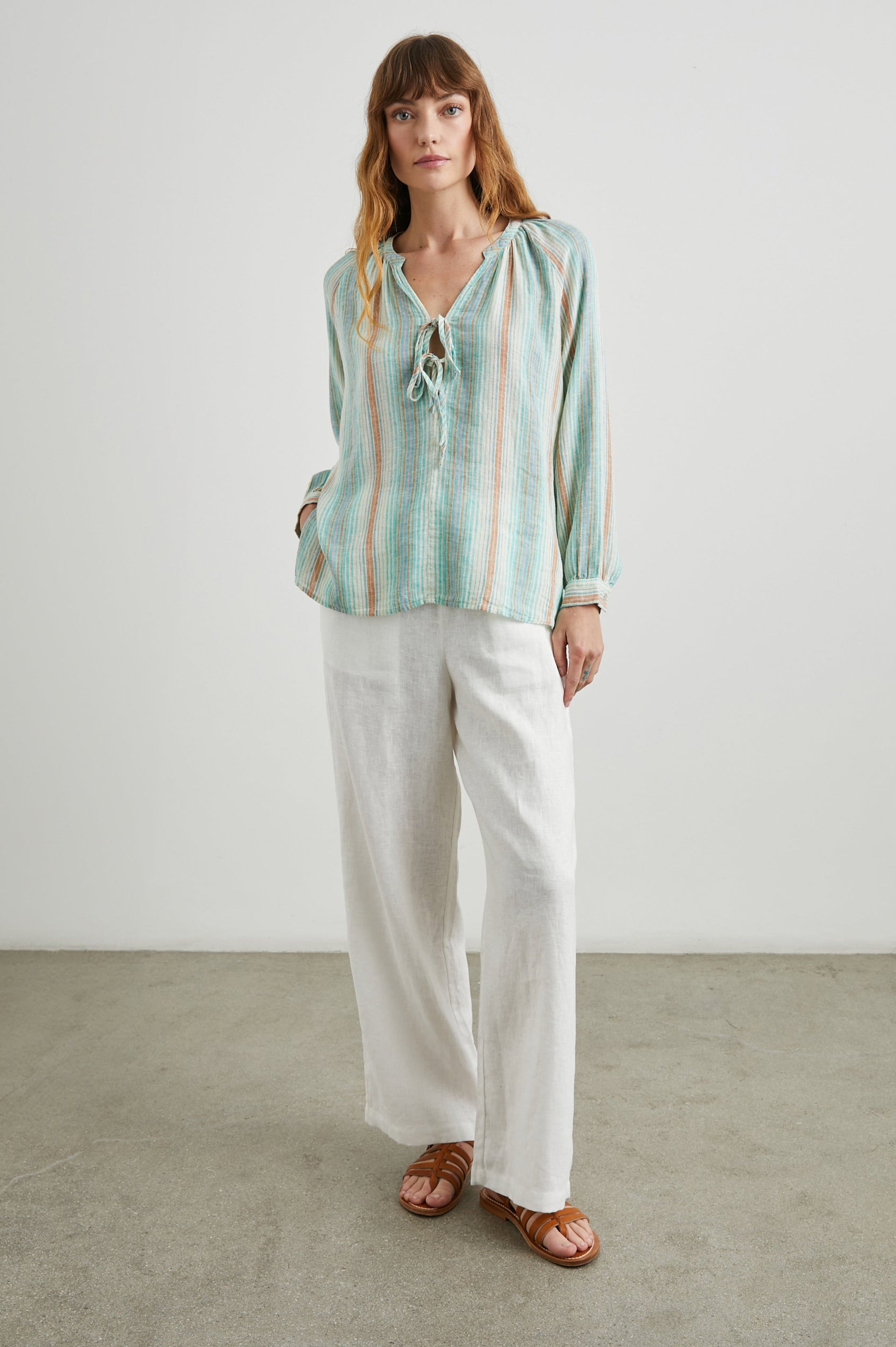 Brielle Long-Sleeve Top with a Deep V Neck with Ties and Pleats around the Neckline in Seaview Stripe Colorway, with vertical stripes in sea green, white and sand - Front Full Body View Featured on Model