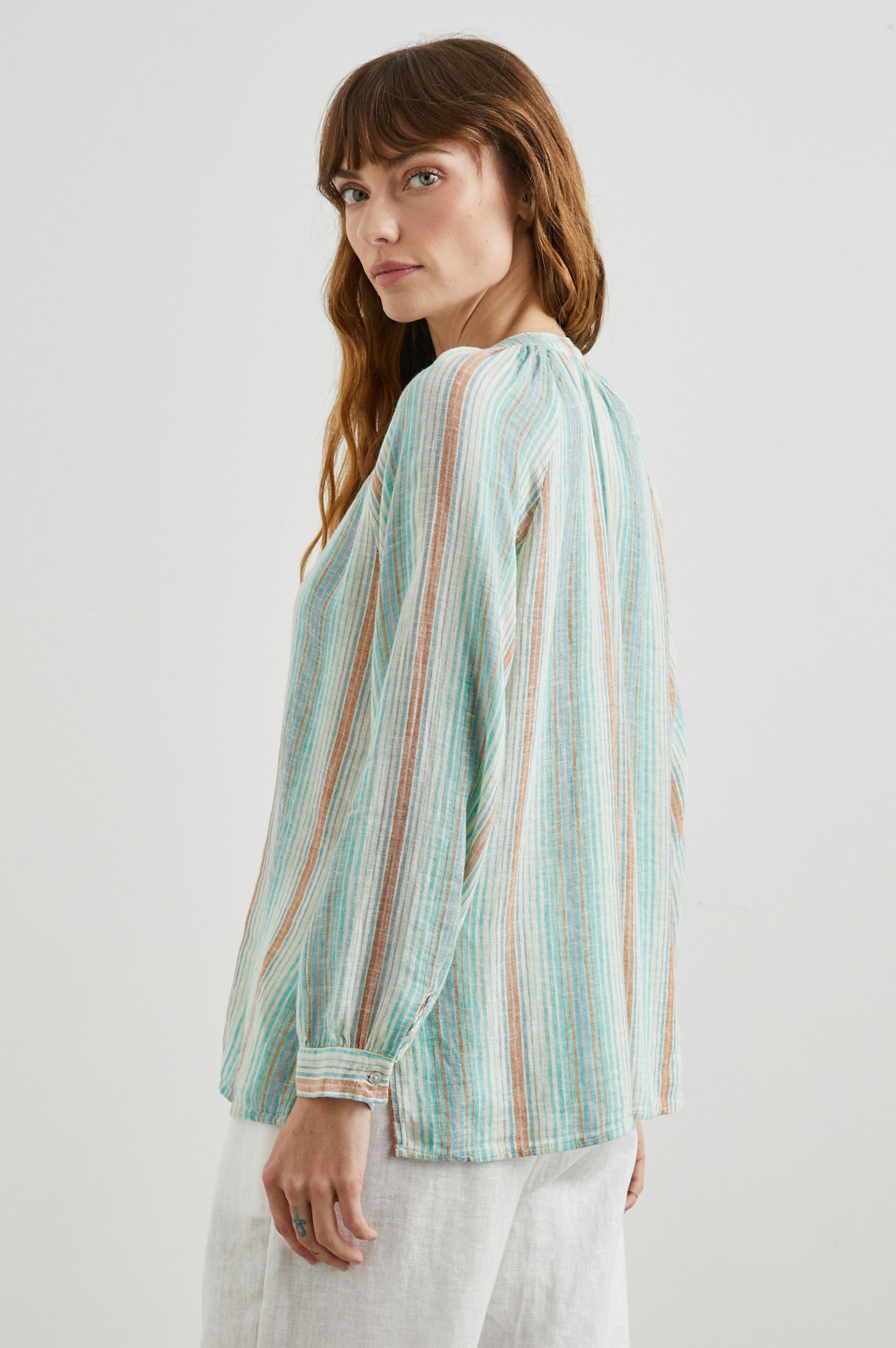 Brielle Long-Sleeve Top with a Deep V Neck with Ties and Pleats around the Neckline in Seaview Stripe Colorway, with vertical stripes in sea green, white and sand - Side View Featured on Model