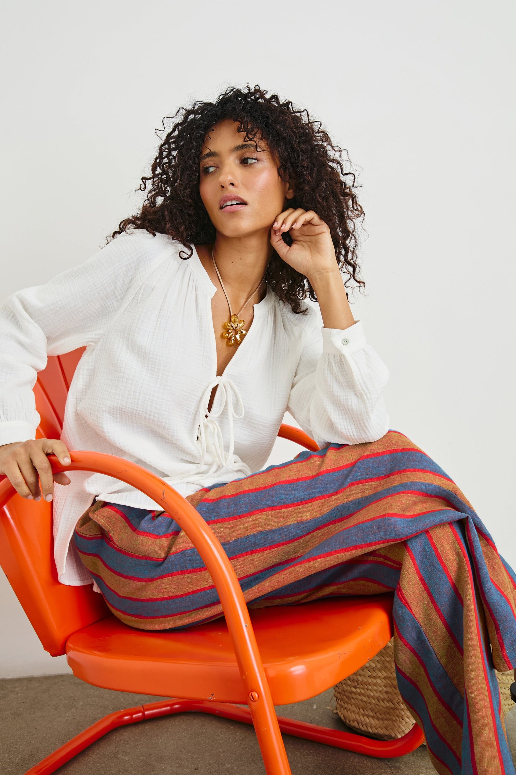 Brielle Long-Sleeve Top with a Deep V Neck with Ties and Pleats around the Neckline in White Colorway - Front View Featured on Seated Model