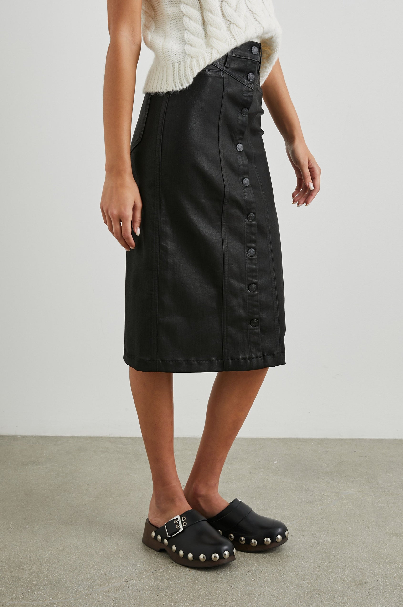 Broadway Midi Skirt with Buttons Down the Front, Belt Loops, Two Front Pockets and Two Back Patch Pockets in Coated Noir Colorway - Side View Featured on Model 