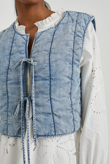 Bronte Sleeveless Cropped Denim Top with Front Tie Closure and Vertical Seams in Medium Cloud Wash Colorway - Front View Featured on Model, Layered Over a Second Shirt 