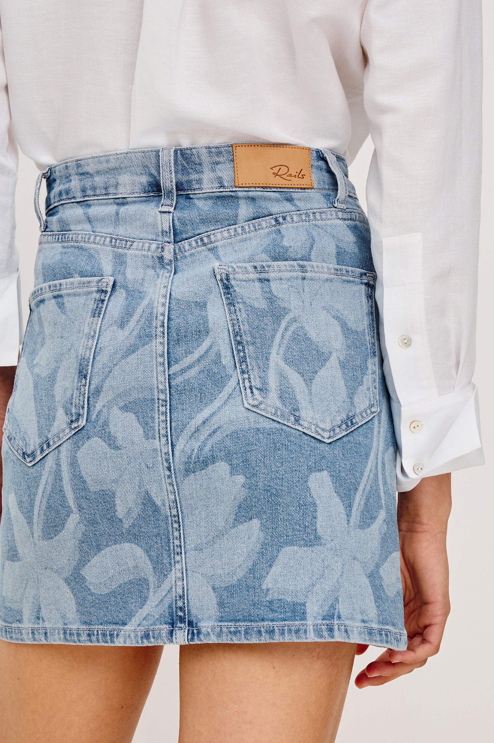 Burbank Mini Skirt in Light Stretch Denim With High Rise, A-Line Silhouette, Front Zip Fly, 5-Pockets, and Embroidered Florals in Floral Laser Colorway - Lower Body Back View Featured on Model