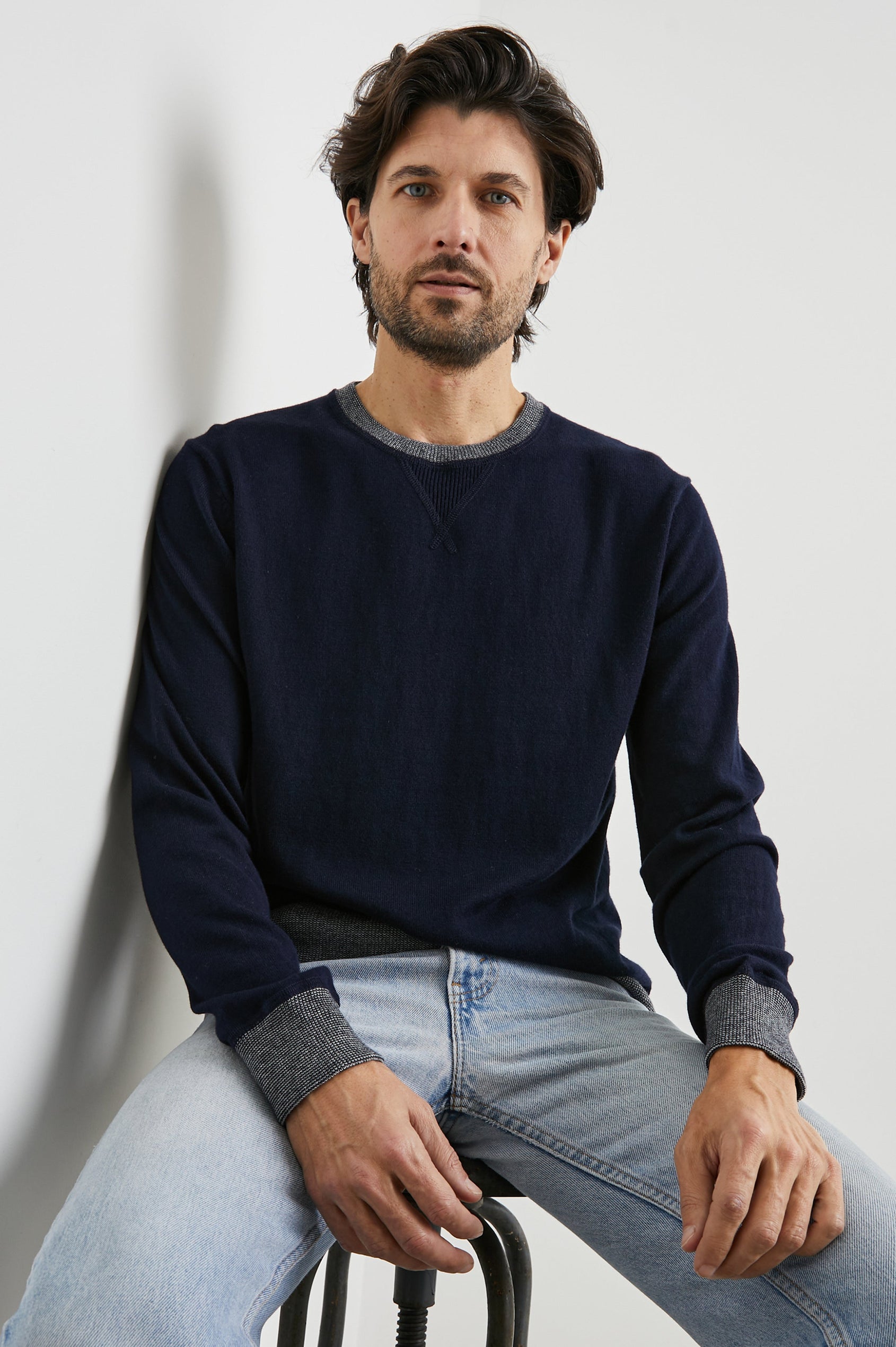 Burns Long-Sleeve Sweater with a Crew Collar and a Lighter Colored Ribbed Trim in Perfect Navy Colorway - Front View Featured on Seated Model