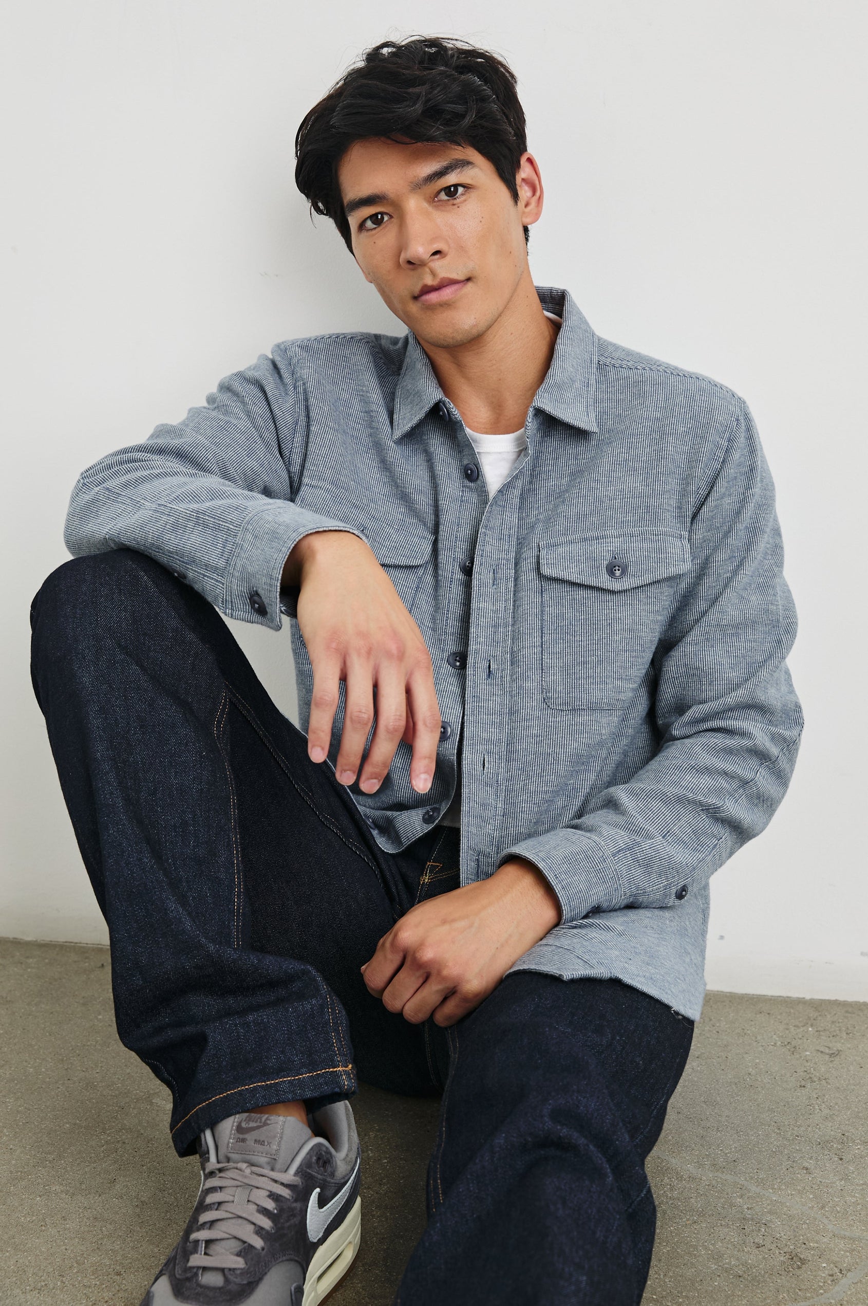 Burr Collared Shirt Jacket with Button Closure, Two Chest Button Flap Pockets and Textured Fabric in Denim White Colorway - Front Unbuttoned Full Body View Featured on Seated Model