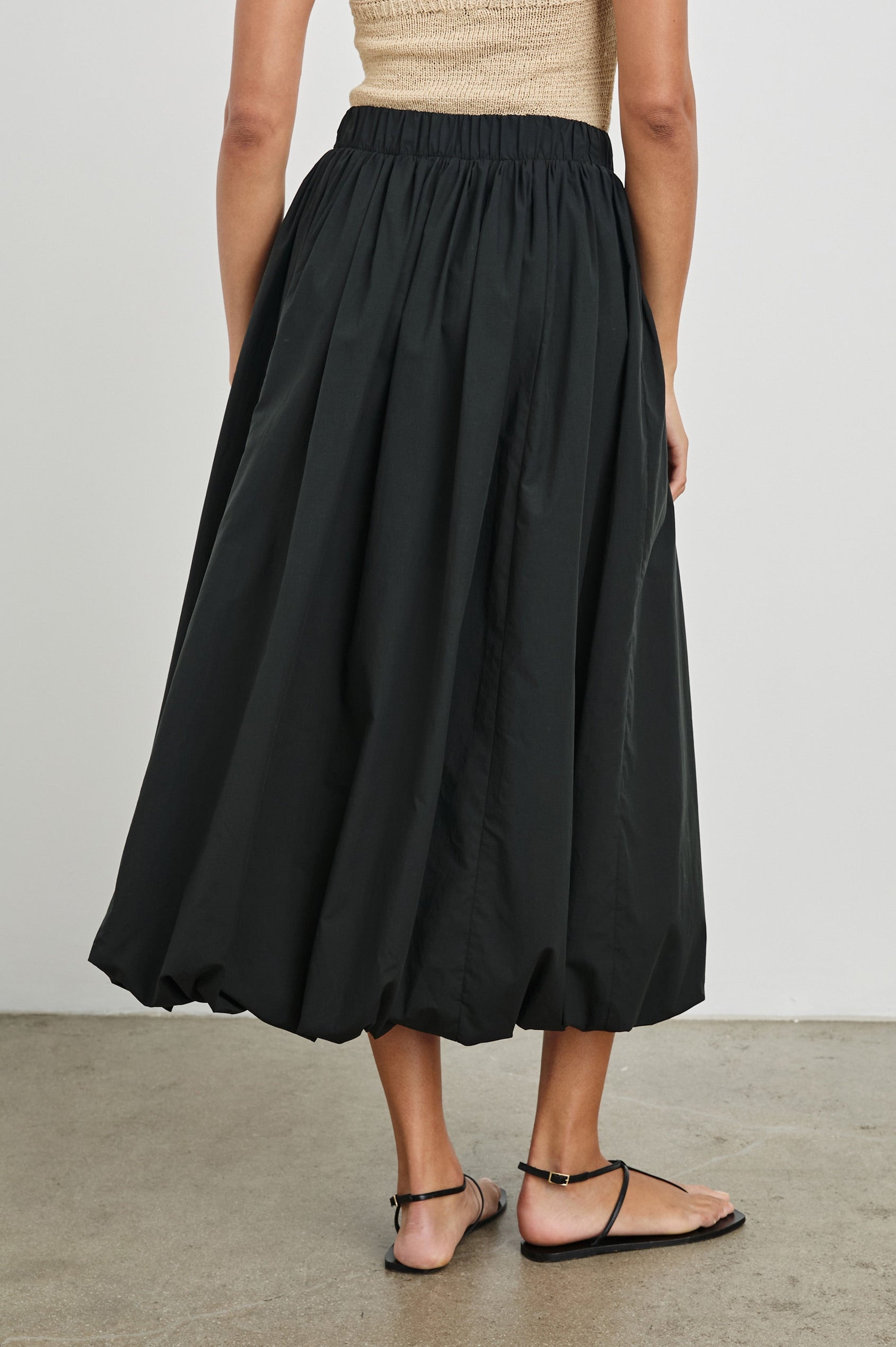 Cala midi length bubble skirt with elastic waistband and side pockets in Black - back view on model 
