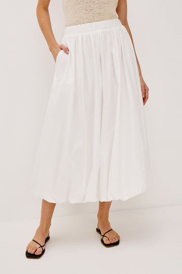 Cala midi length bubble skirt with elastic waistband and side pockets in White Colorway - front view on model.