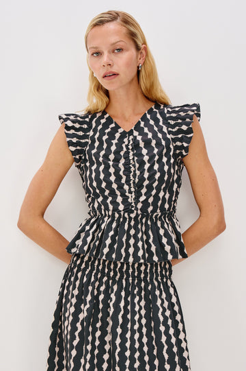 Cali short sleeve top with center front ruching, flutter sleeves, and a ruffle hem in Painted Noir colorway - front view on model