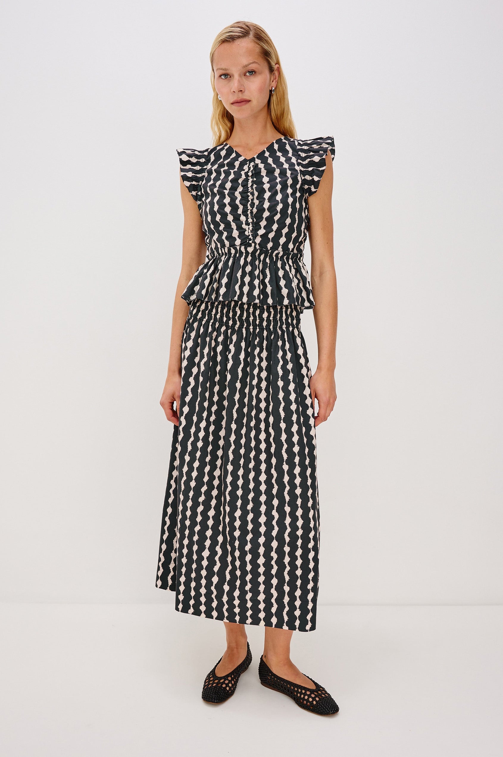 Cali short sleeve top with center front ruching, flutter sleeves, and a ruffle hem in Painted Noir colorway - full body front view on model