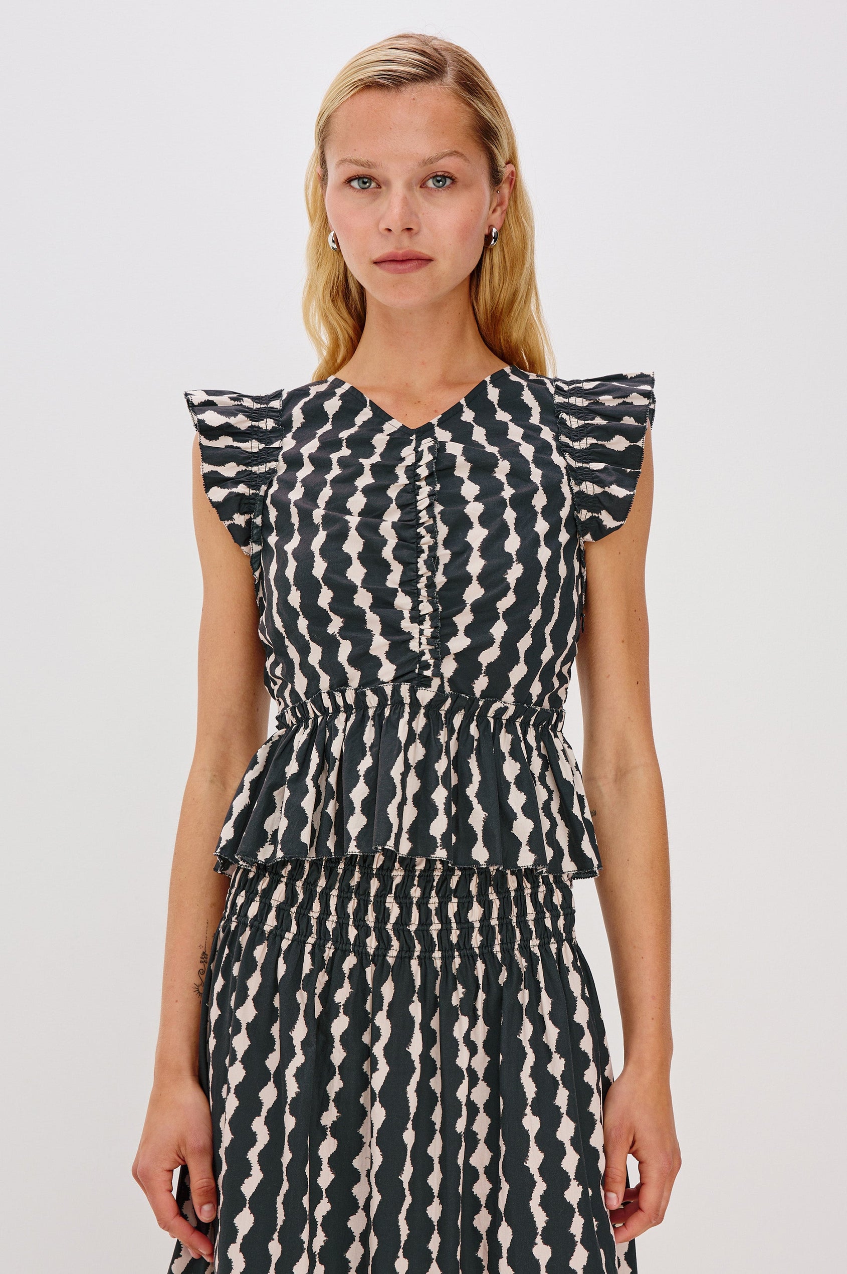 Cali short sleeve top with center front ruching, flutter sleeves, and a ruffle hem in Painted Noir colorway - front view on model