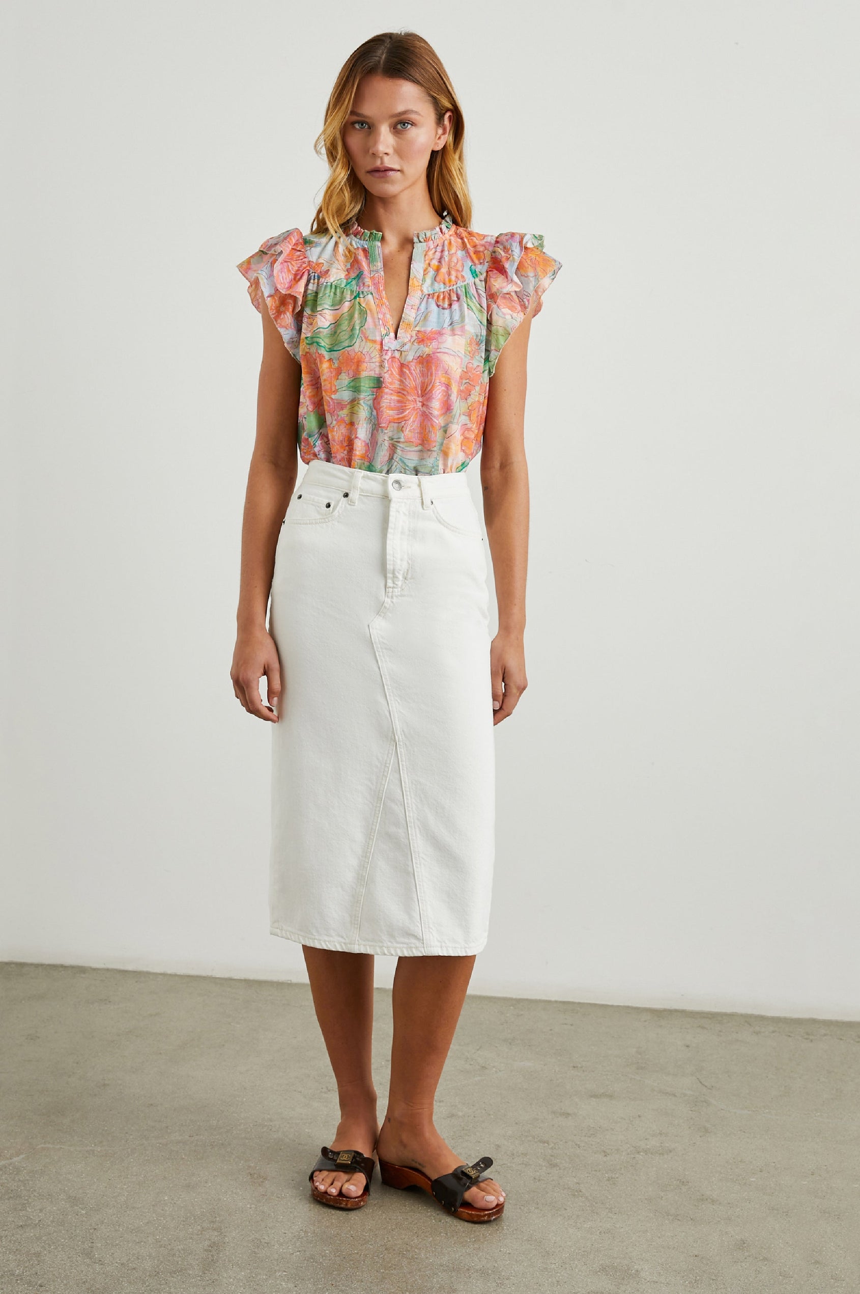 Calista Short Sleeve Top with Double Layer Flutter Sleeves, a V Neck with a Placket, a Ruffled Collar, and Light Ruching Along the Yoke in Tropics Colorway, Floral Print in Oranges, Greens and Blue - Front Tucked Full Body View Featured on Model 