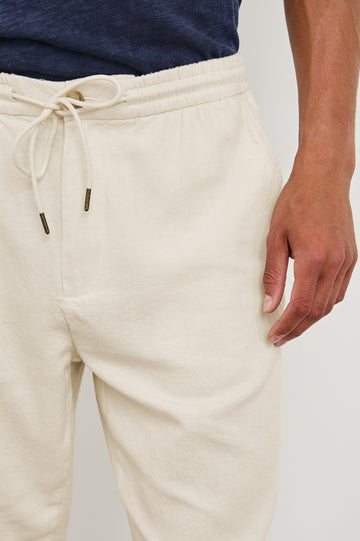 Callum extended length linen straight leg pant with elastic waistband and adjustable drawstring in Ecru - close up of details on model