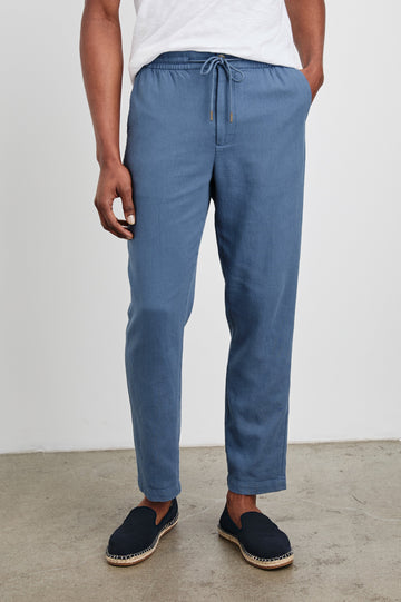Callum Pants with a Drawstring Waist, Two Front Pockets and a Back Patch Pocket in Washed Blue Colorway - Front View Featured on Model.