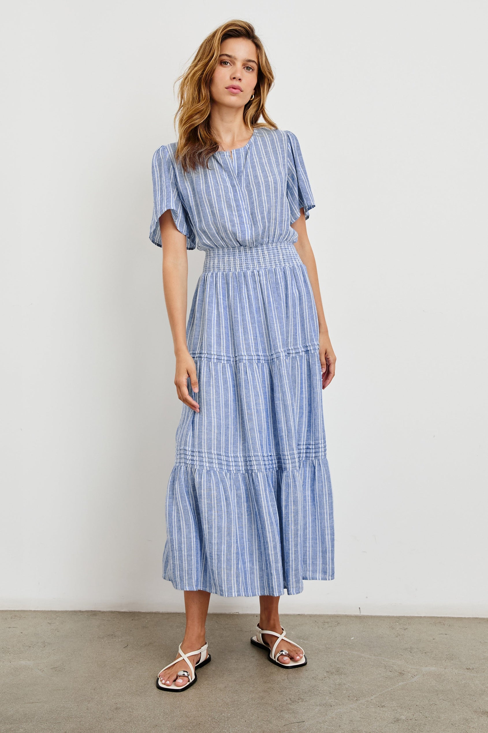 Cannes Short-Sleeve Midi Dress with a Shirred Waist, Tiered Skirt and Short Slit at Neck in Lake View Stripe Colorway, vertical stripes in blues and white - Front Full Body View Featured on Model