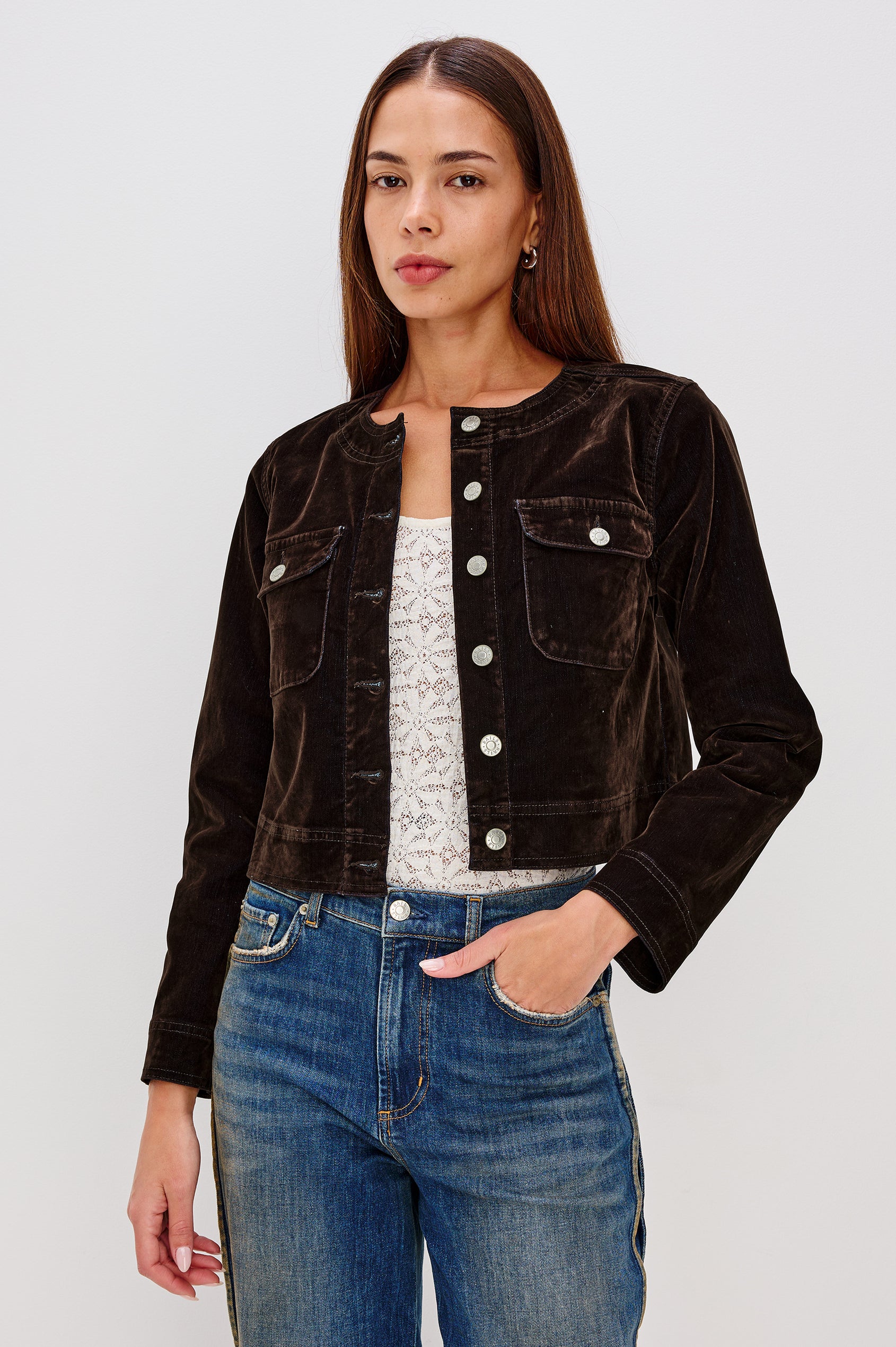 The Capistrano is a cropped denim jacket with a crewneck, it has a button front and two chest pockets in Chocolate Flocking colorway. Front view featured on model.