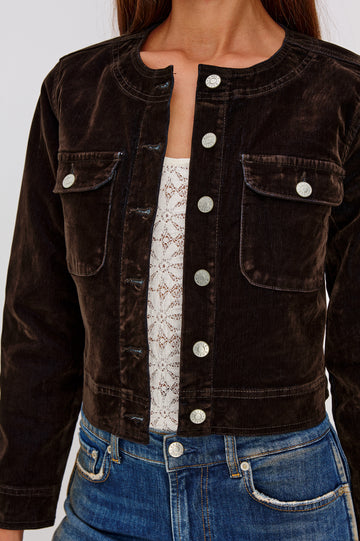 The Capistrano is a cropped denim jacket with a crewneck, it has a button front and two chest pockets in Chocolate Flocking colorway. Front detail view featured on model.