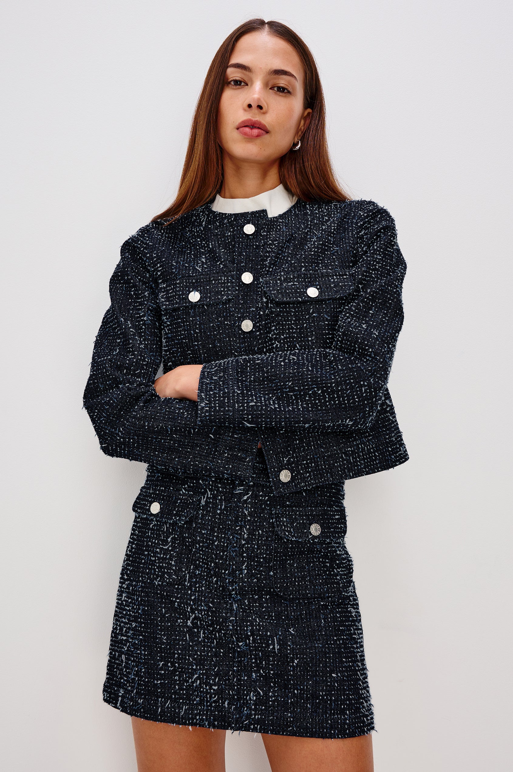 The Capistrano is a cropped denim jacket with a crewneck, it has a button front and two chest pockets in Denim Tweed colorway. Front view featured on model.