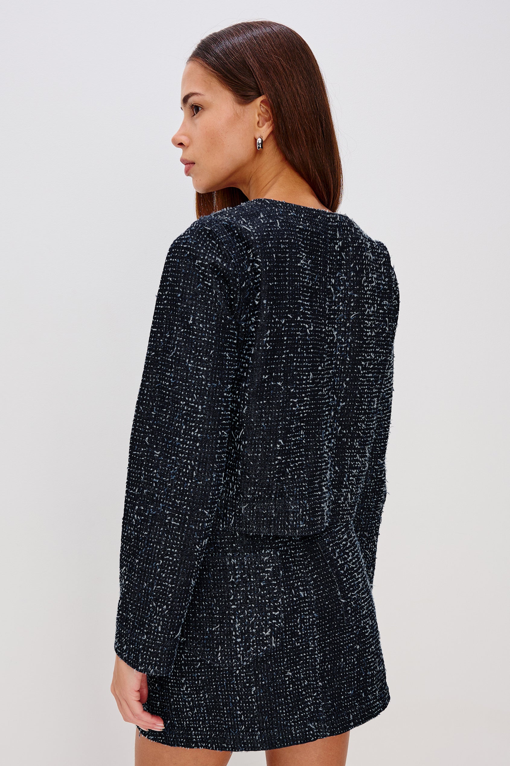 The Capistrano is a cropped denim jacket with a crewneck, it has a button front and two chest pockets in Denim Tweed colorway. Back view featured on model.