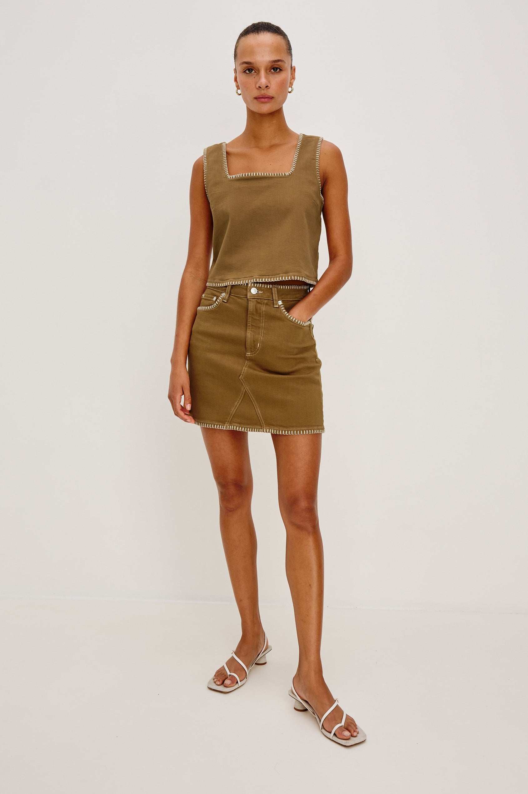 Laurel 5-Pocket Colored Denim Mini Skirt With Blanket Stitch Along All Edges in Safari Embroidered. Front View Shown on Model.