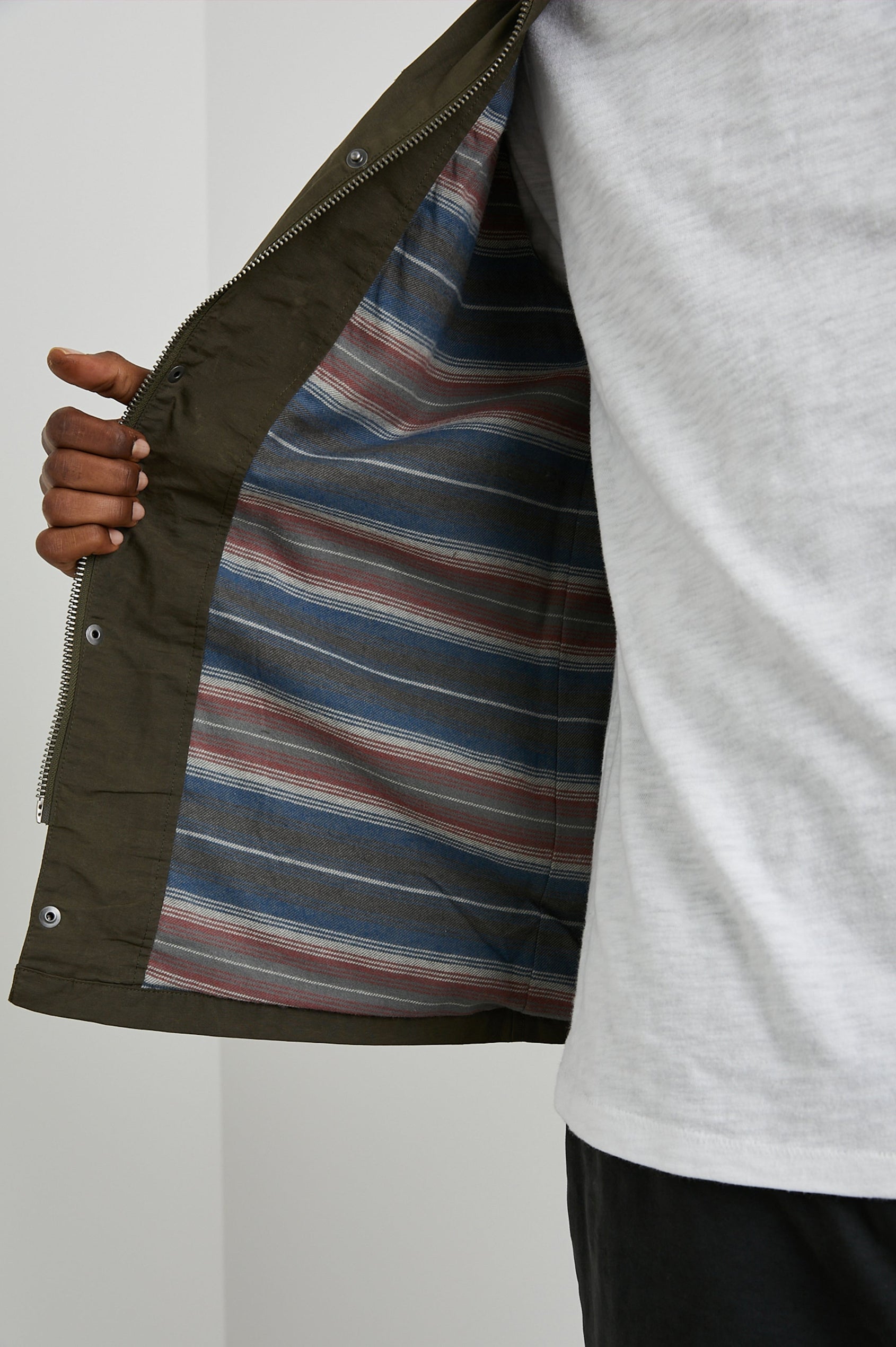 Cardiff Jacket with a Snap and Zipper Closure, Two Chest Snap Flap Pockets and Two Front Snap Flap Pockets in Dark Olive Colorway, with an Interior of Multicolor Horizontal Stripes - Front Interior View Featured on Model  