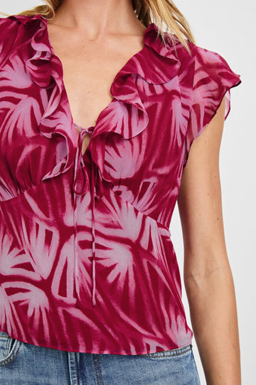 Carmine Top with Flutter Sleeves, Deep V Neck with a Tie, and a Ruffled Neckline in Bahia Colorway, a print with shades of pink - Front View Featured on Model