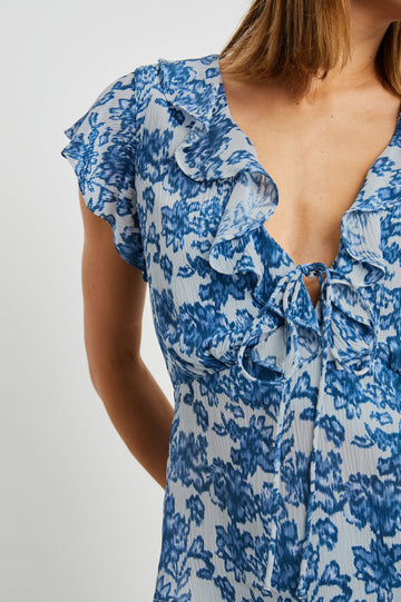 Carmine Top with Flutter Sleeves, Deep V Neck with a Tie, and a Ruffled Neckline in Chambray Floral Colorway, Chambray flowers on white - Front View Featured on Model