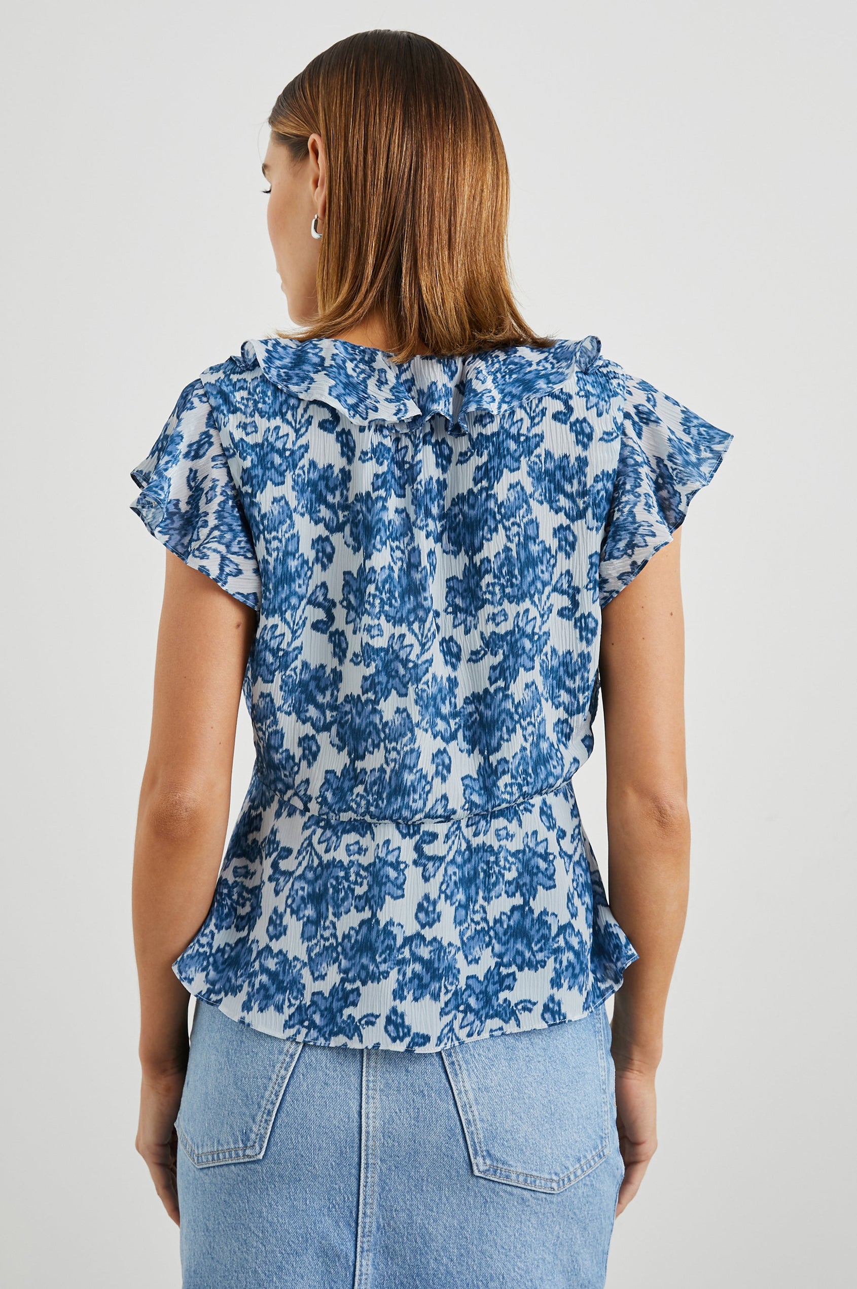 Carmine Top with Flutter Sleeves, Deep V Neck with a Tie, and a Ruffled Neckline in Chambray Floral Colorway, Chambray flowers on white - Back View Featured on Model