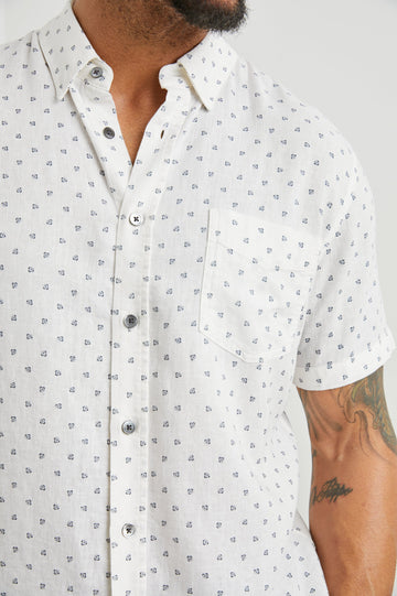 Carson Short Sleeve Button Up with a Chest Patch Pocket in Autumn Calico White Colorway, Small Blue Flowers on White- Front View Featured on Model
