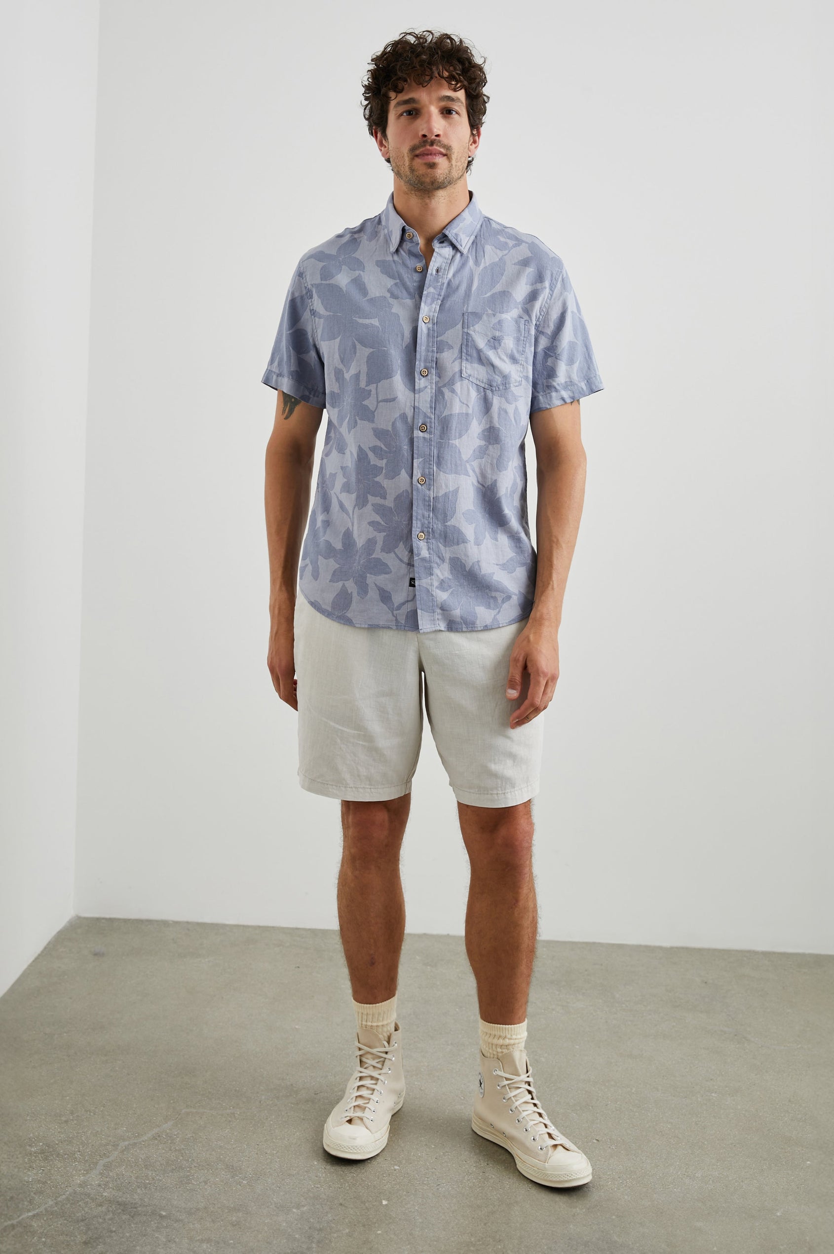 Carson Short Sleeve Button Up with a Chest Patch Pocket in Garden Sands Orchid Colorway, Blue Flowers on Light Blue - Front Full Body View Featured on Model
