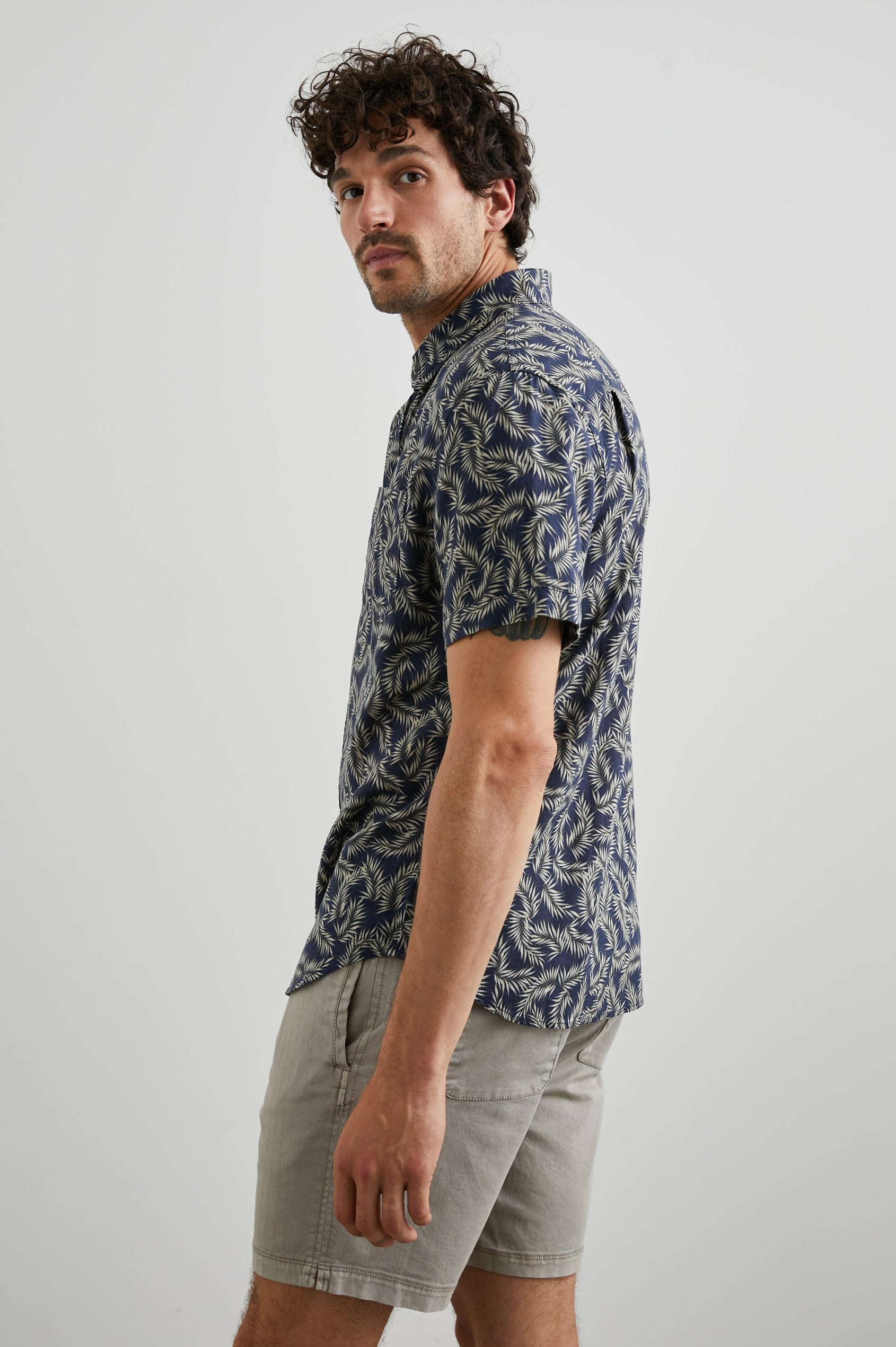Carson Short Sleeve Button Up with a Chest Patch Pocket in Palm American Navy Colorway, Tan Fronds on Navy - Side View Featured on Model