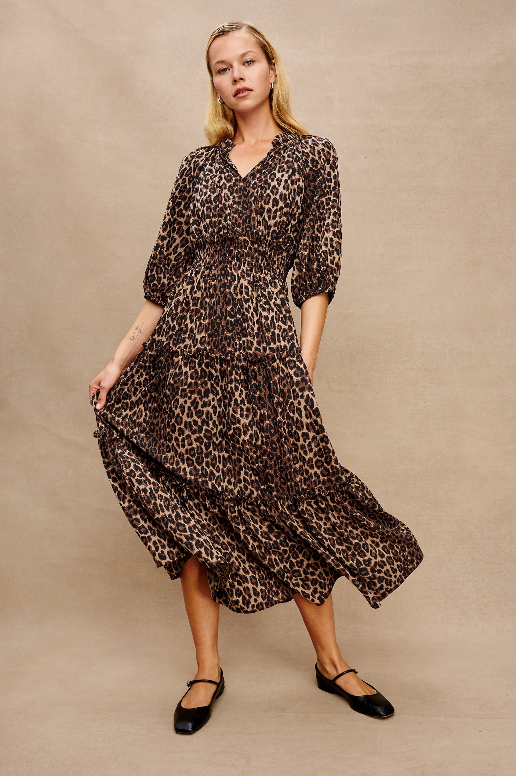 Caterine Maxi Dress with Mid-length Sleeves, a V neck, a Shirred Collar with a tie, a Smocked Waist, and a Tiered Skirt in Brown Nala Colorway - Stylized Full Body Front View Featured on Model, in Motion