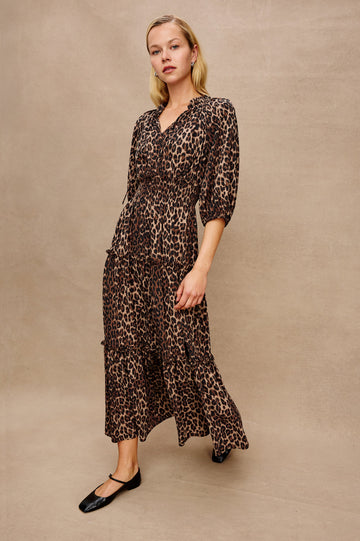 Caterine Maxi Dress with Mid-length Sleeves, a V neck, a Shirred Collar with a tie, a Smocked Waist, and a Tiered Skirt in Brown Nala Colorway - Stylized Front View Featured on Model
