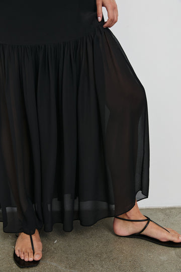 Chandra Maxi Tank Dress with Spaghetti Straps and a Contrast Semi Sheer Fabric Gathered Hem in Black Colorway. Front Detailed View Shown on Model.