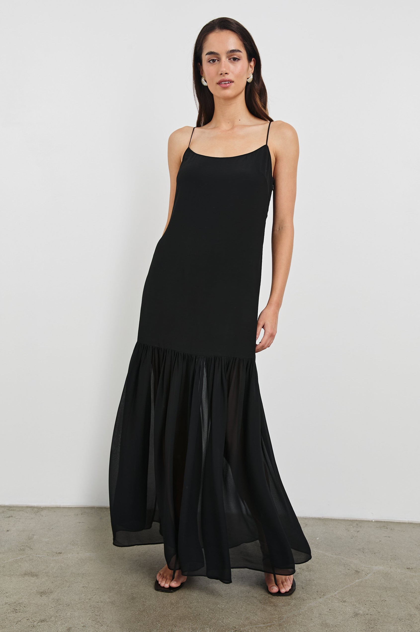 Chandra Maxi Tank Dress with Spaghetti Straps and a Contrast Semi Sheer Fabric Gathered Hem in Black Colorway. Full Body Front View Shown on Model.