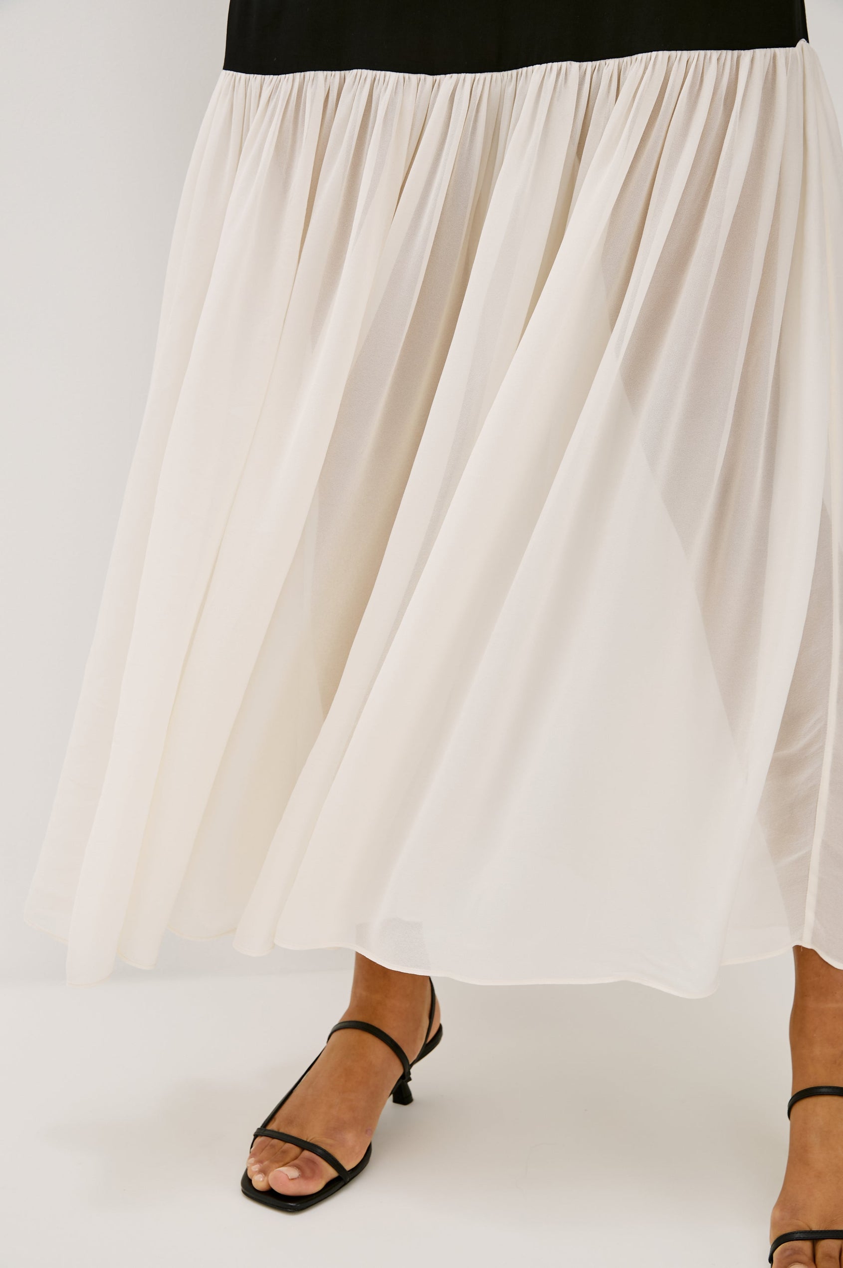 Chandra Maxi Tank Dress with Spaghetti Straps and a Contrast Semi Sheer Fabric Gathered Hem in Black Ivory Colorway - close up of bottom hem details on model