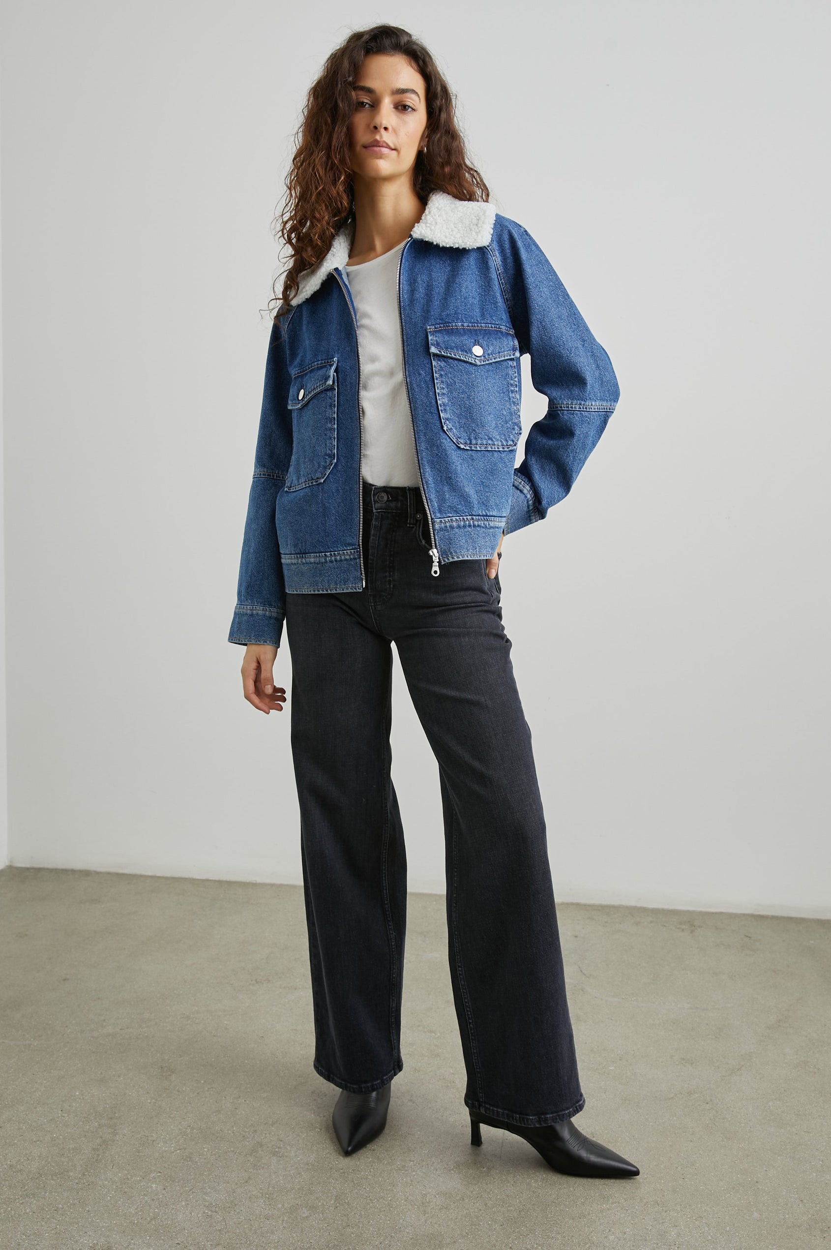 Cheyenne Zip-Up Denim Jacket with Two Buttoned Chest Flap Pockets, and Faux Shearling Collar in Indigo Sherpa Colorway - Front Full Body View Featured on Model 