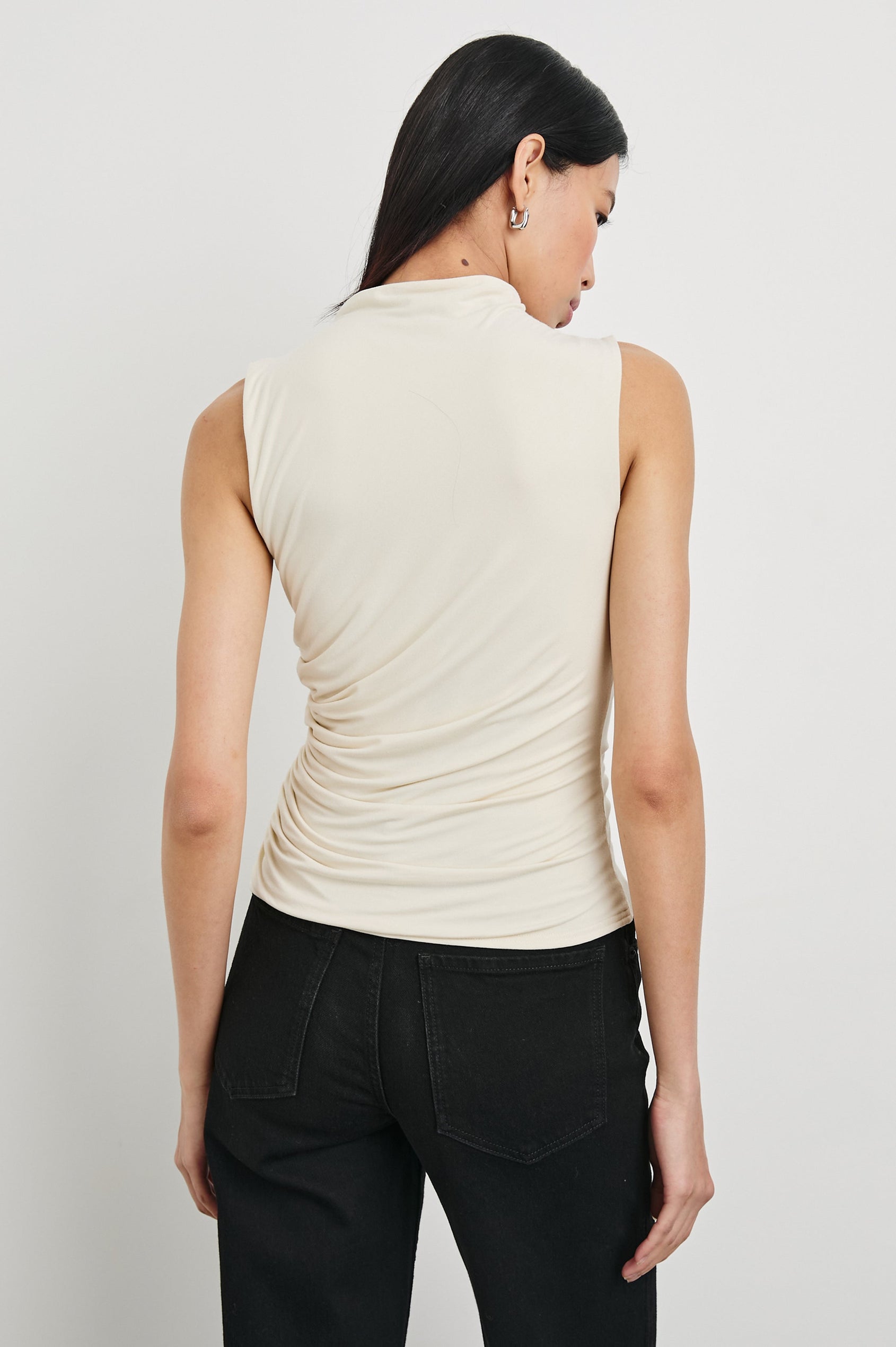 Christen Sleeveless Top with a Mock Neck and Ruching Along One Side Seam in Ivory Colorway - Back View Featured on Model