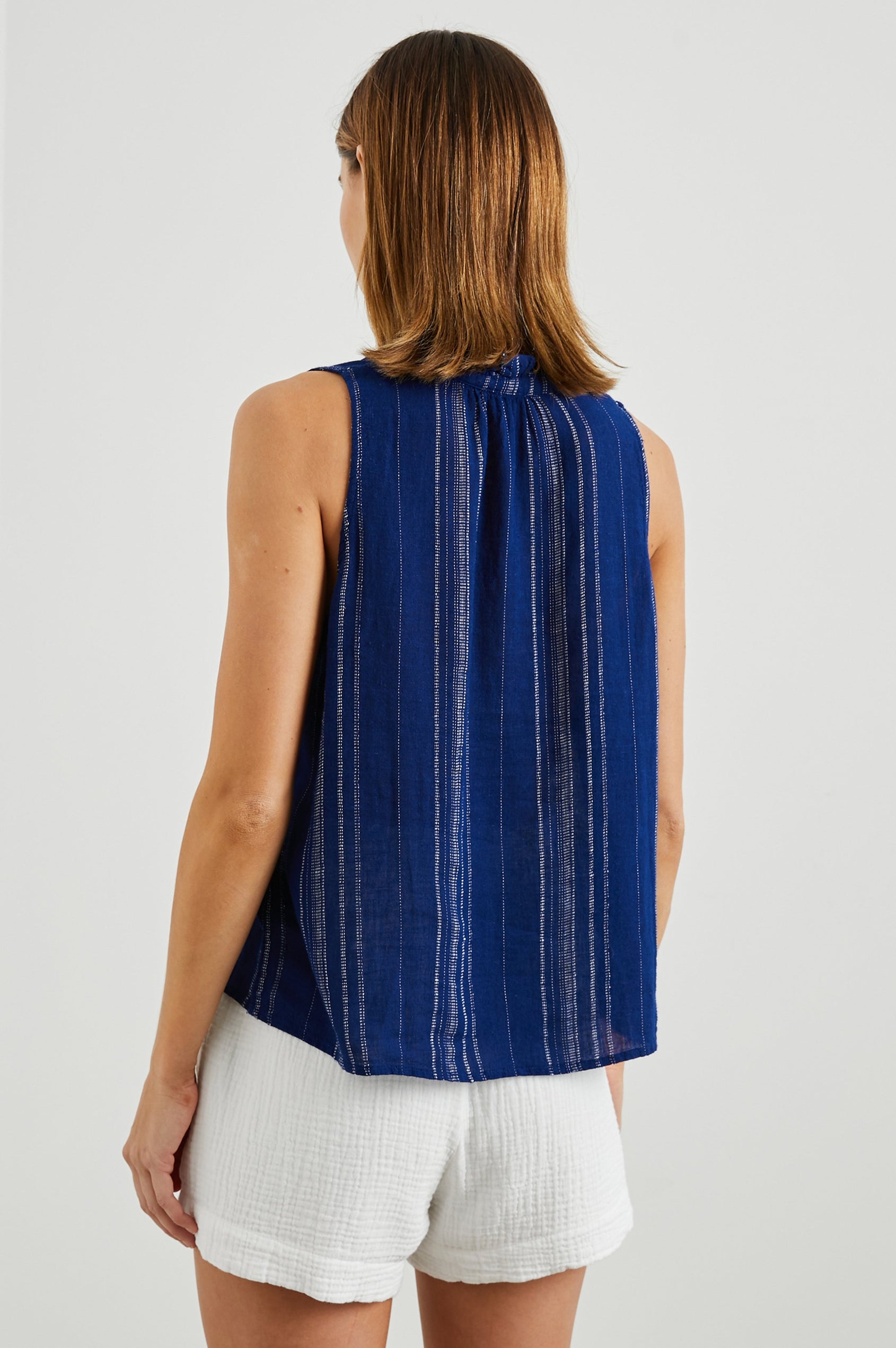 Christy Sleeveless Tank Top, with a V Neck and a Ruched Collar in Noja Stripe Colorway, Thin Vertical White Stripes on Blue - Back View Featured on Model
