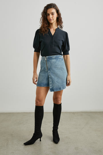 Cienega Denim Mini Skirt with an Asymmetrical Hem and a Wrap Appearance with a Diagonal Zipper in Geranium Colorway - Front Full Body View Featured on Model 