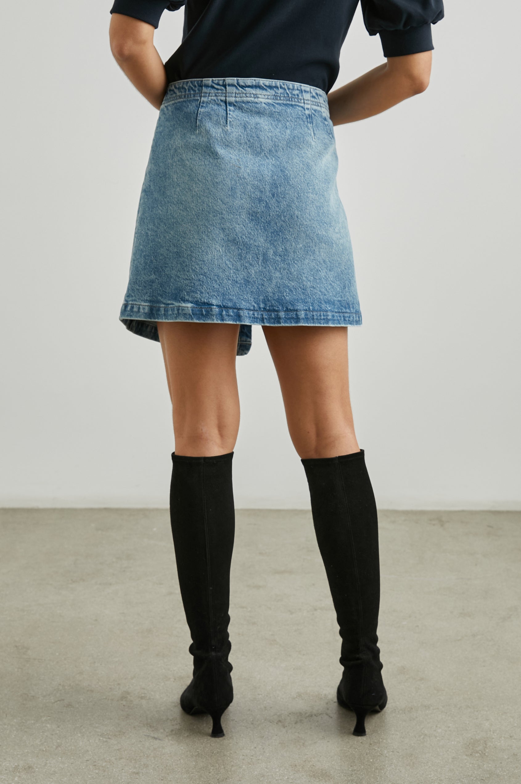 Cienega Denim Mini Skirt with an Asymmetrical Hem and a Wrap Appearance with a Diagonal Zipper in Geranium Colorway - Back View Featured on Model 