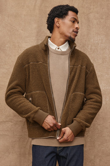 The Clark is a zip front brushed back polar fleece and details include contrast stitching, two zipper pockets, and contrast  grey ribbed cuffs in Lichen colorway. Front view featured on model.